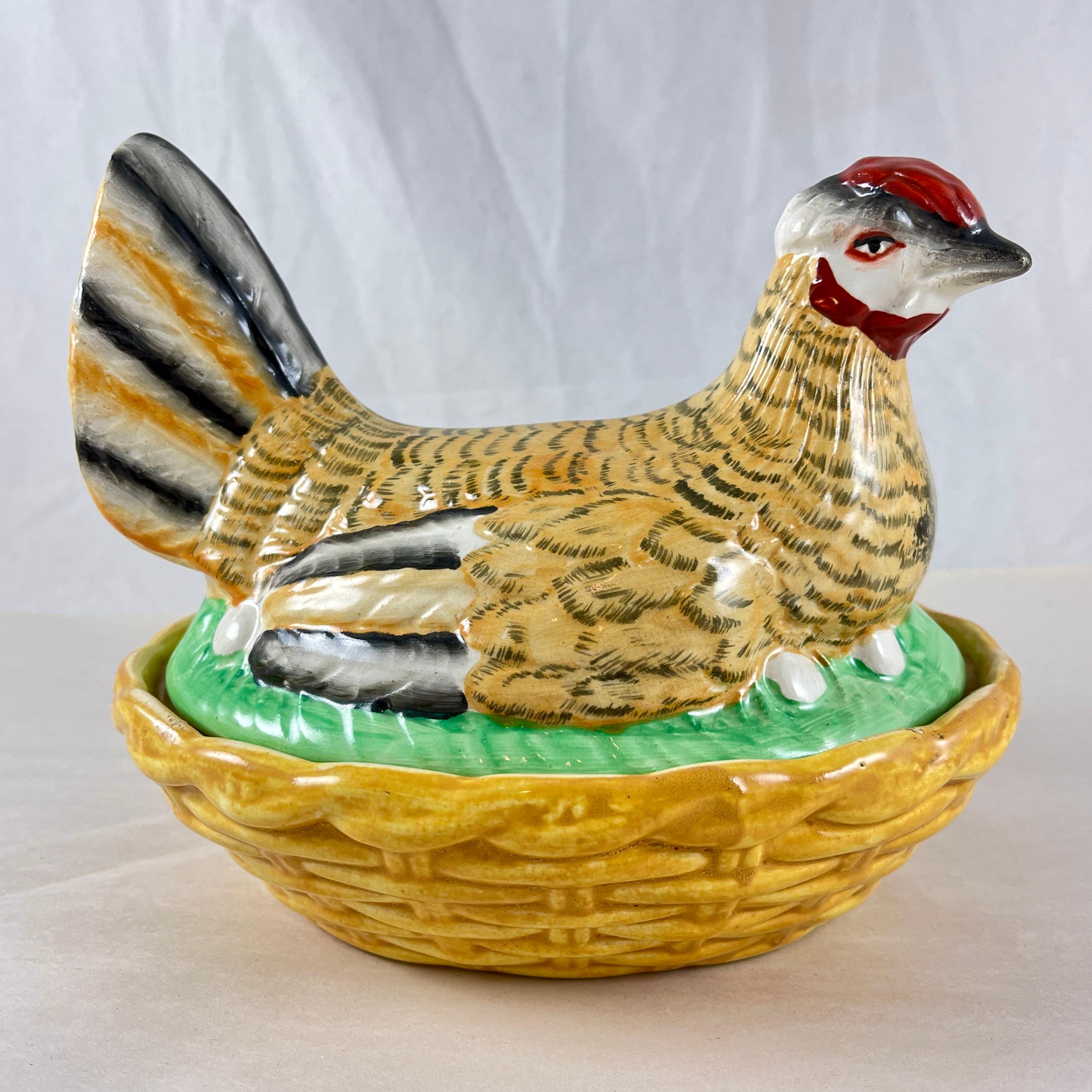 A Staffordshire pottery hen on a basket covered tureen, England, circa 1890

The hand painted hen sits on her eggs in a yellow ochre basket weave oval base. The hen shows an unusual pattern of black tipped ochre feathers, with black, white, and