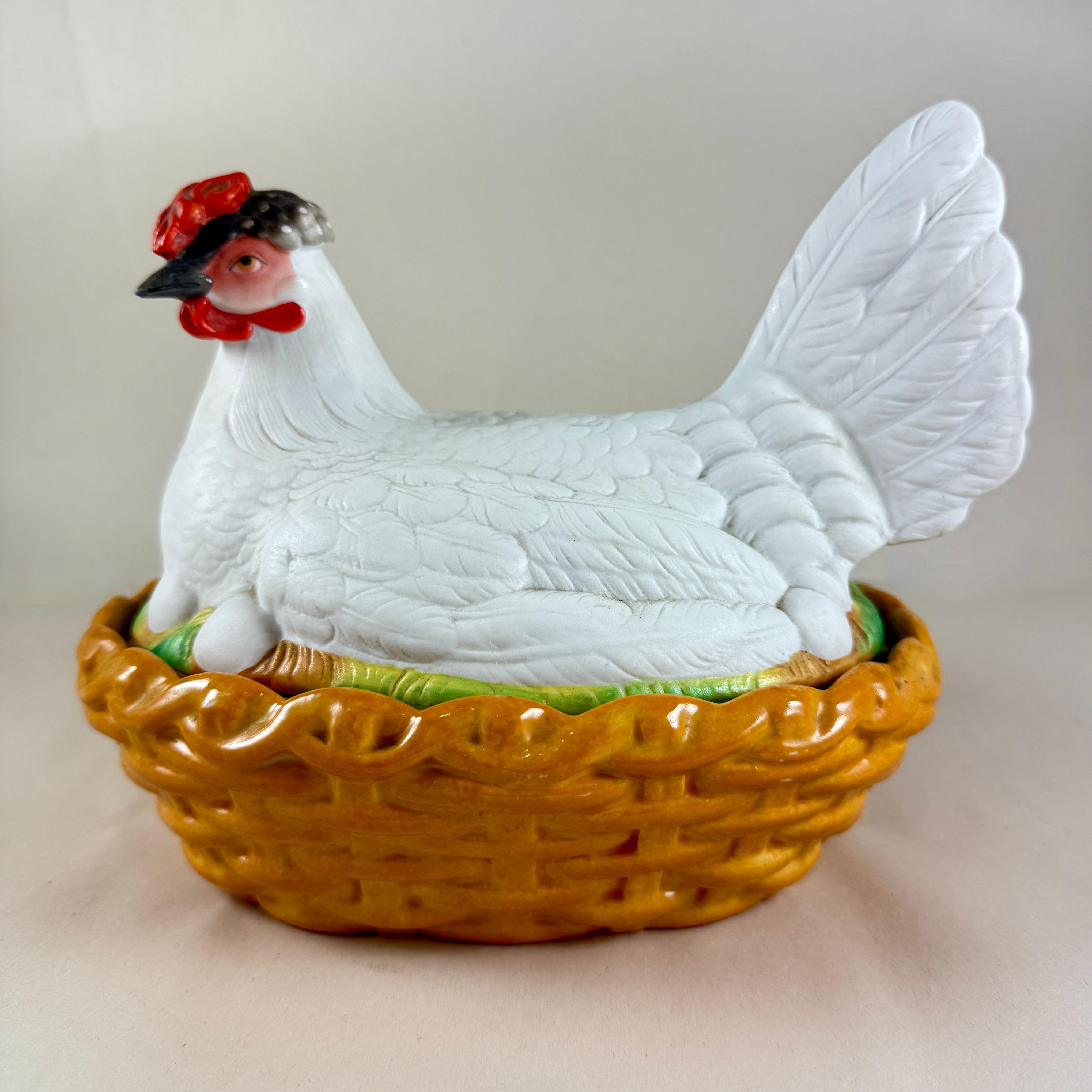 Une poule en poterie du Staffordshire sur une soupière couverte d'un panier, Angleterre, vers 1890

La poule en biscuit peinte à la main est assise sur ses œufs dans une base ovale en tressage de panier brun terre de Sienne. La poule présente un