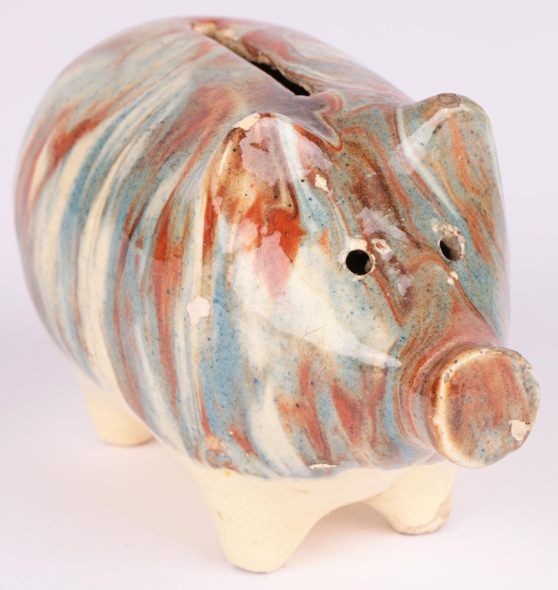 A delightful antique English Staffordshire pottery pig moneybox decorated in marble effect slipware glazes and dating from around 1840. The moneybox shaped as a standing pig stands on four short stump legs with a large pig shaped body with molded