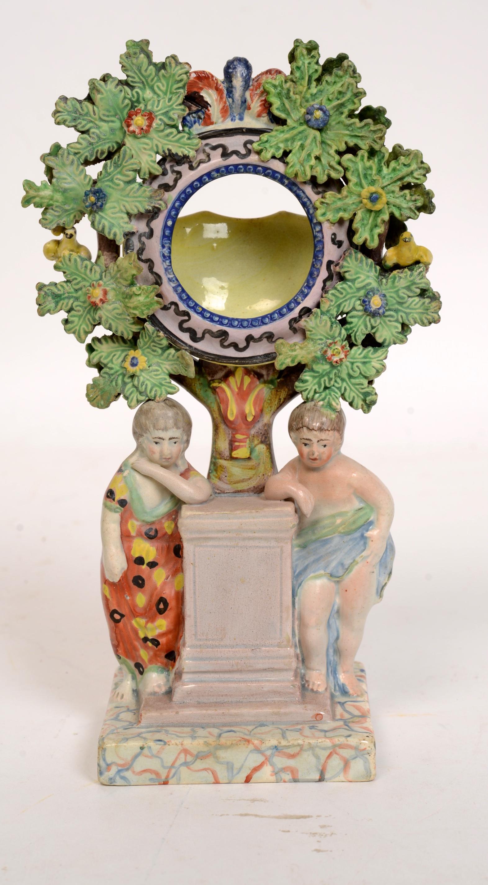 Staffordshire Pearlware Bocage figure watch holder, circa 1820. It is decorated in the round, (to the front and back.) This is a fine example of a Staffordshire pottery pearlware watch holder with two cherubs flanking a pillar, the watch holder is