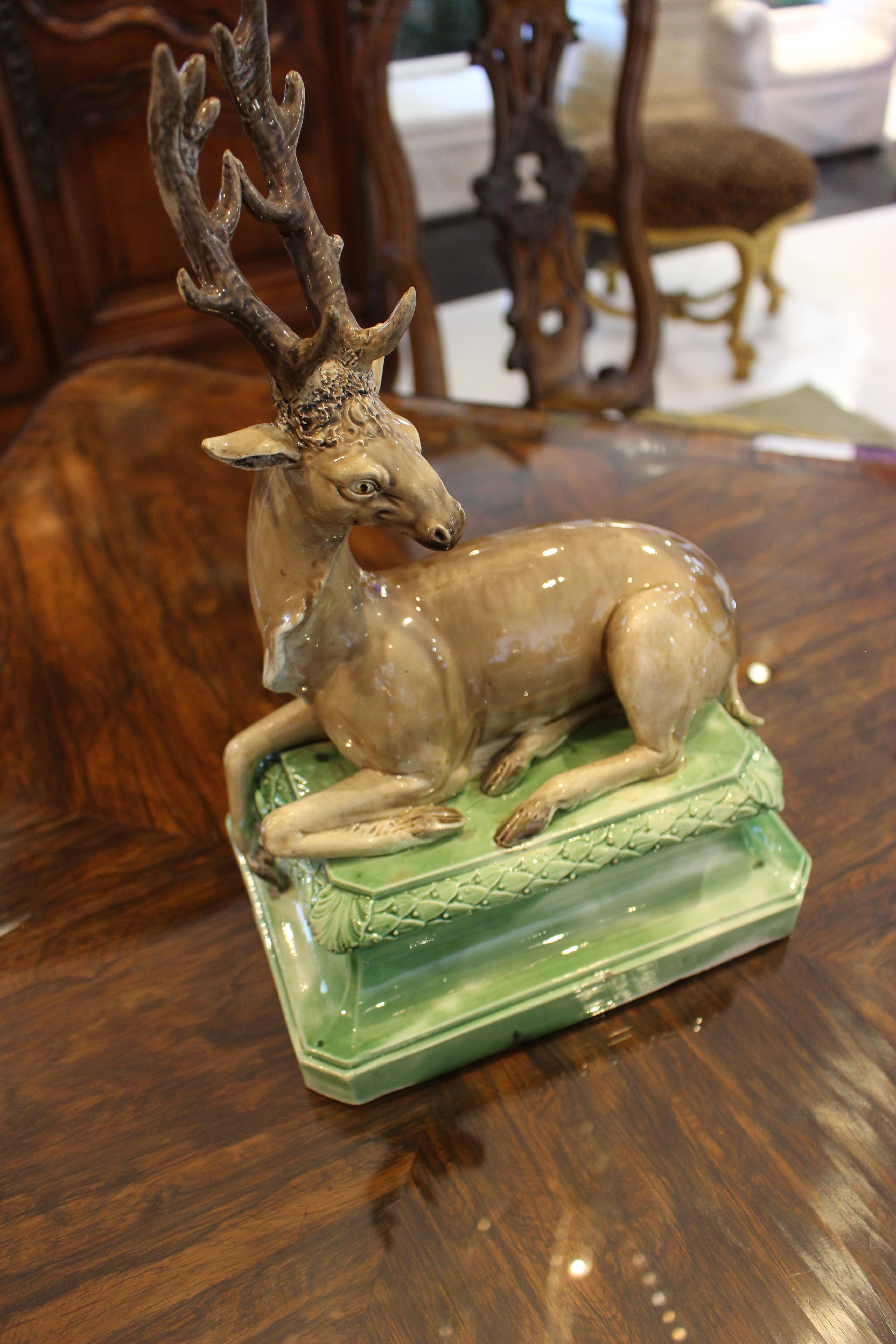 Modèle en céramique perlée de Staffordshire représentant un cerf assis sur une base rectangulaire à pansement vert. De la collection de Peggy et David Rockefeller. Vers 1770.