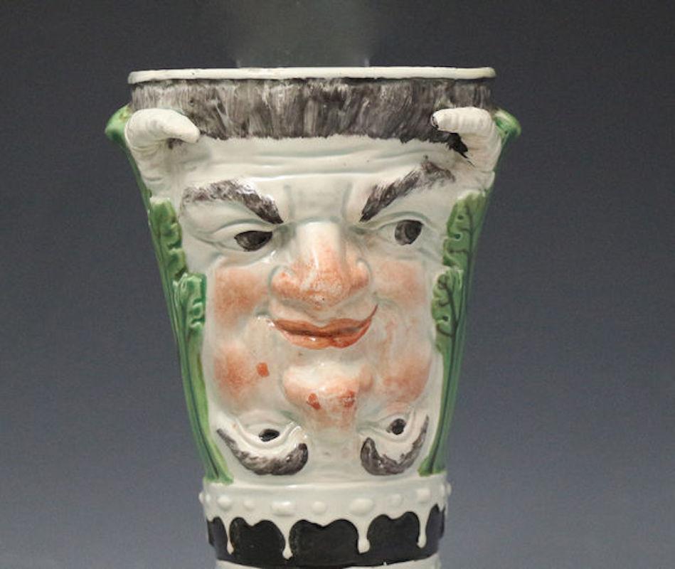 An amusing satirical anti-Catholic Staffordshire pearl ware pottery metamorphose stirrup or Ryton cup made in early 19th century. The cup has reversible heads of the Pope and the Devil. The Pope is shown wearing his triple crown headgear and the
