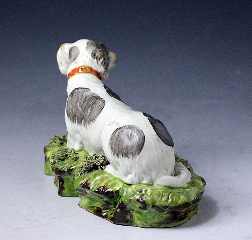 Dated: circa 1820 Staffordshire England

Staffordshire pottery pearlware glazed figure of a setter dog in repose on an oblong base with shredded clay and applied leaf decorations. The modeling is well executed capturing the sweet nature of this