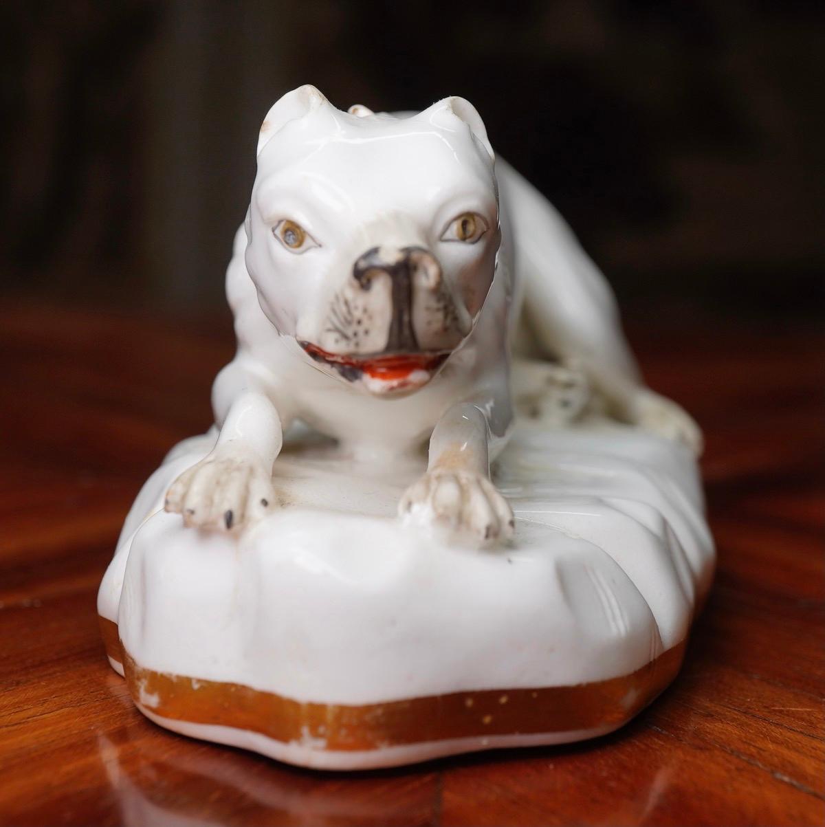 Staffordshire porcelain dog, modelled lying down on a rocky plinth, a gilt collar to his neck. Possibly Alcock
circa 1830.