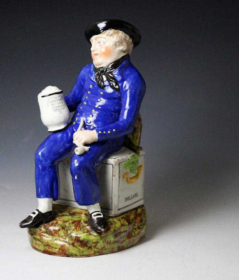 Staffordshire pottery large size American Sailor Toby jug with enamel coloured decoration and pearlware glaze. Staffordshire England, 1815.

The figure is modelled wearing a blue tunic and sitting on a chest with the inscription Dollars. He is