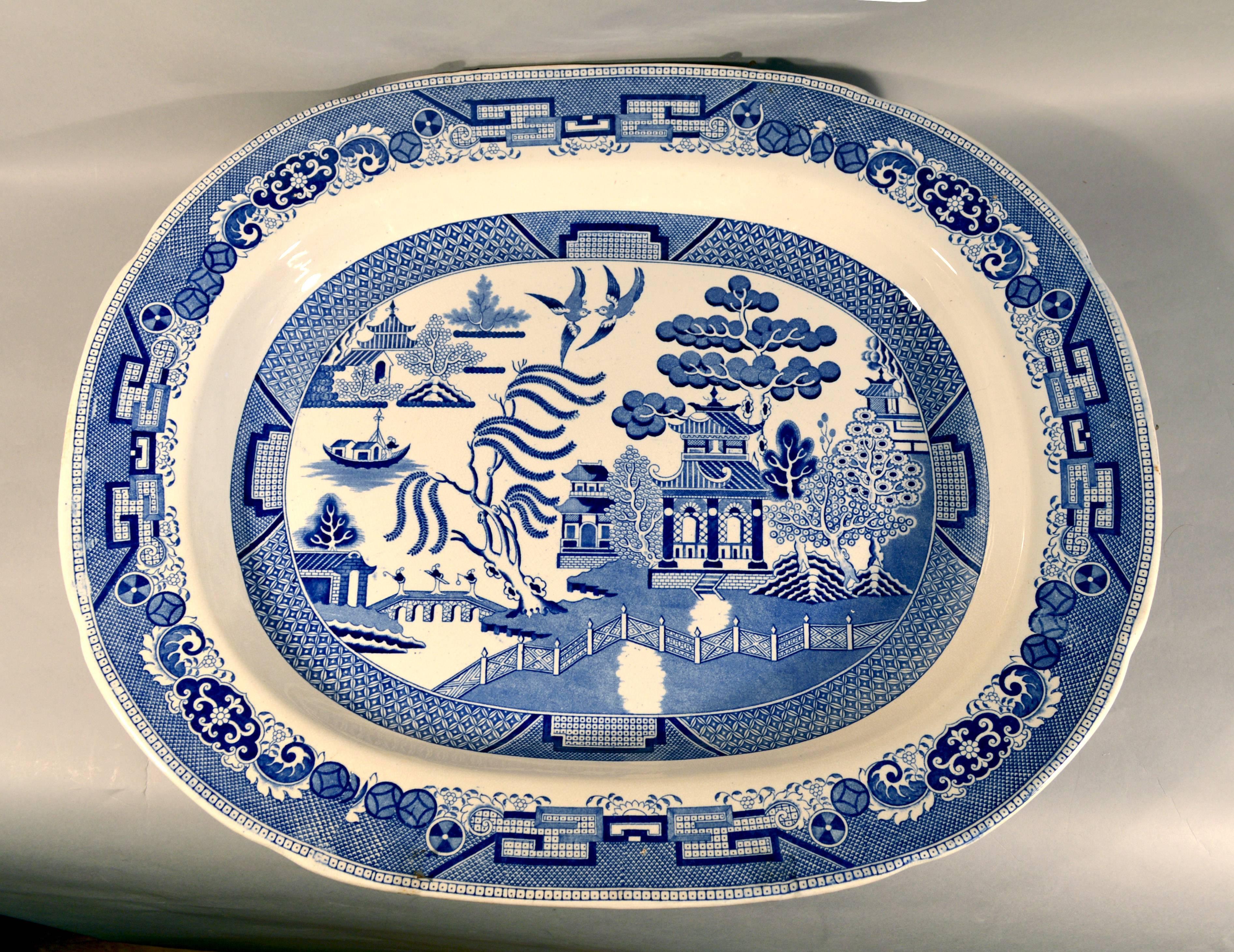 Staffordshire large pottery blue and white large printed chinoiserie dish, 
19th Century

The Staffordshire underglaze blue and white deep dish is printed with a chinoiserie scene of a pagoda amongst trees and with a zig-zag fence in the foreground
