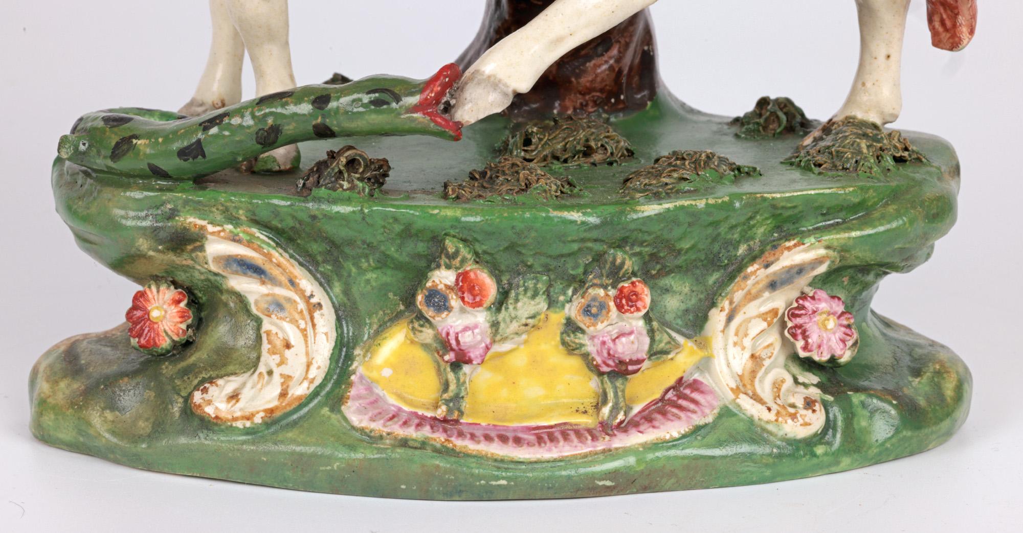 A rare and impressive antique Staffordshire bocage pottery figure of a cow being attacked by a snake, in the style of Ralph Wood and dating from the early 19th century. The hand-crafted pottery figure of a large cow stands raised on an oval shaped