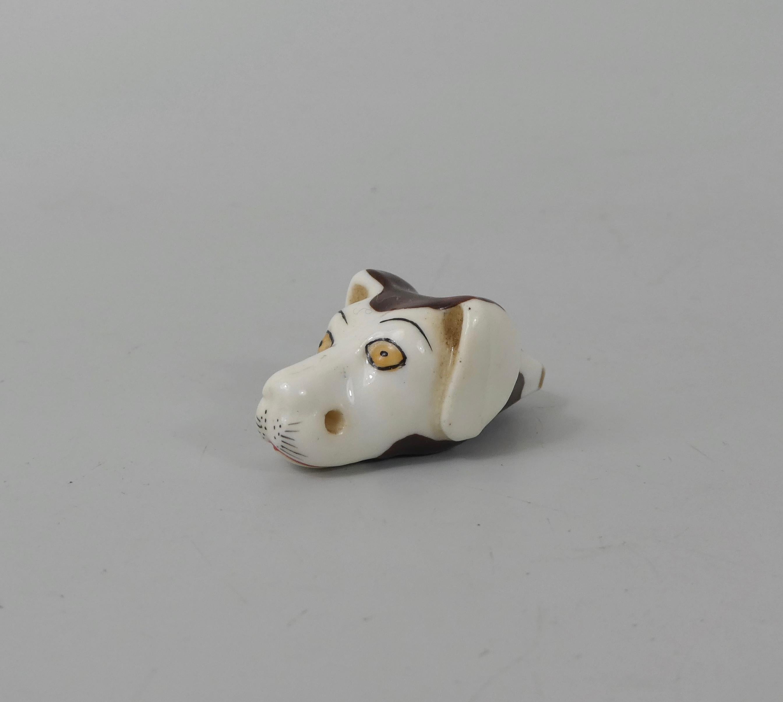 Staffordshire porcellaneous dog whistle, circa 1830. The dogs head well modelled, and painted with yellow eyes and large brown spots. Having a gilt line to the mouthpiece, and pierced at the muzzle, for suspension from a chain.
Measures: Length - 3