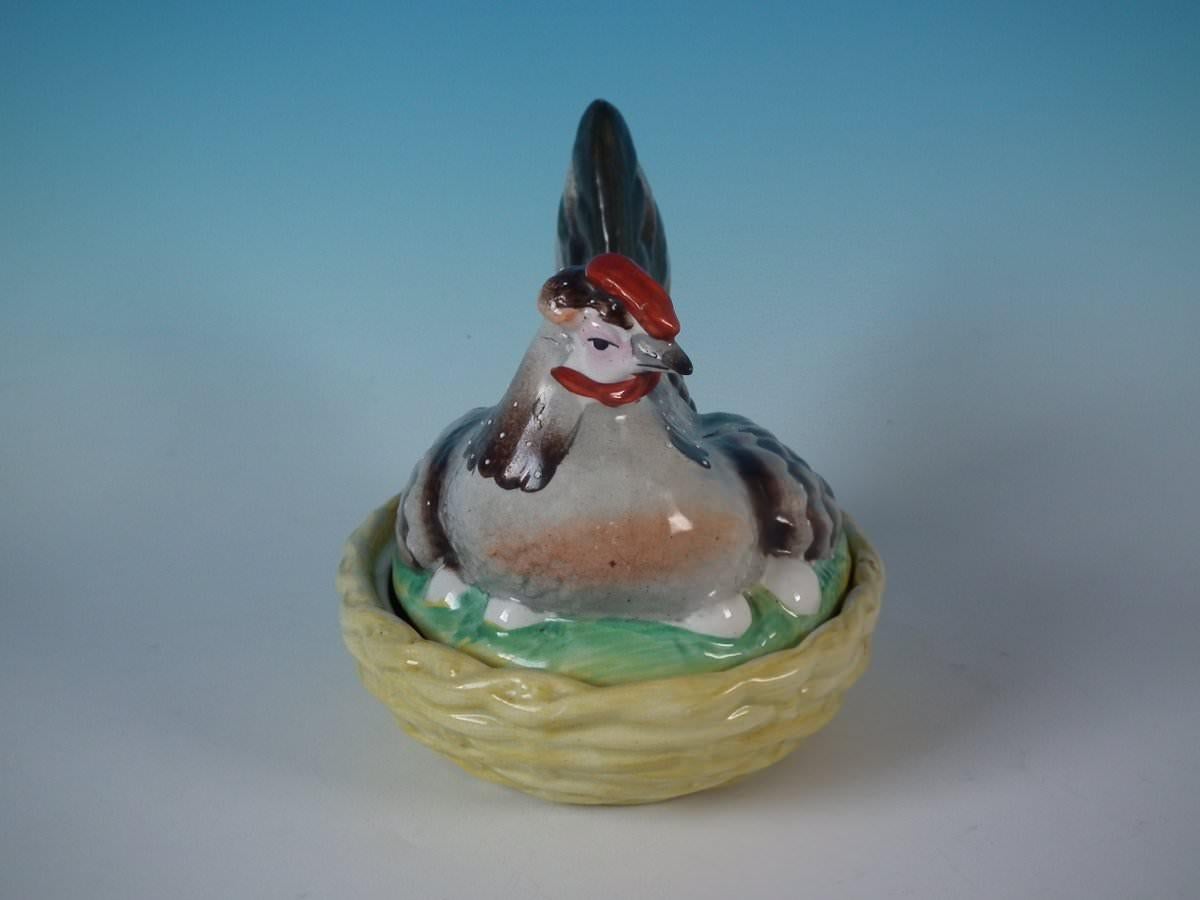 Staffordshire pottery egg tureen and cover which features a hen sitting on her eggs, seated on a basket weave oval base. Multi-coloured version. Decorated 'in the round' - decoration to front and reverse.