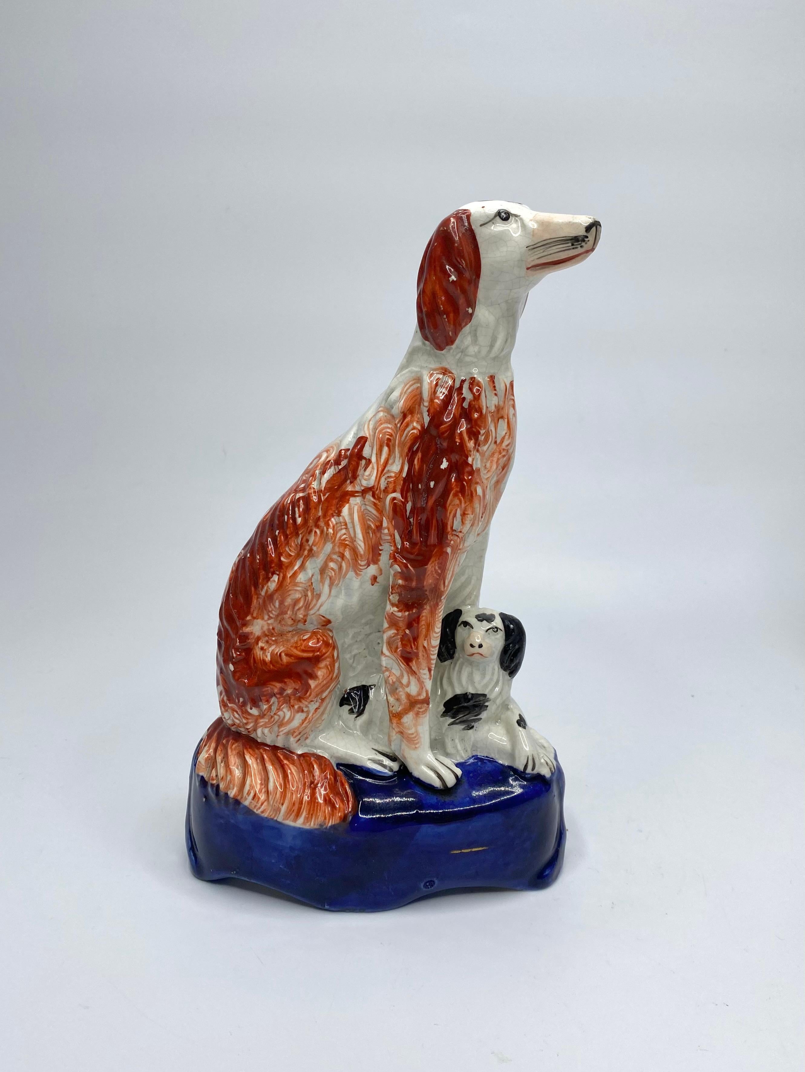 A pair of Staffordshire pottery Irish Setters, and puppies, c. 1850. Elegantly modelled as two tall, seated Irish Setters, their hair well delineated, and painted with liver red spots, feathered at the edges. They sit, with recumbent puppies at