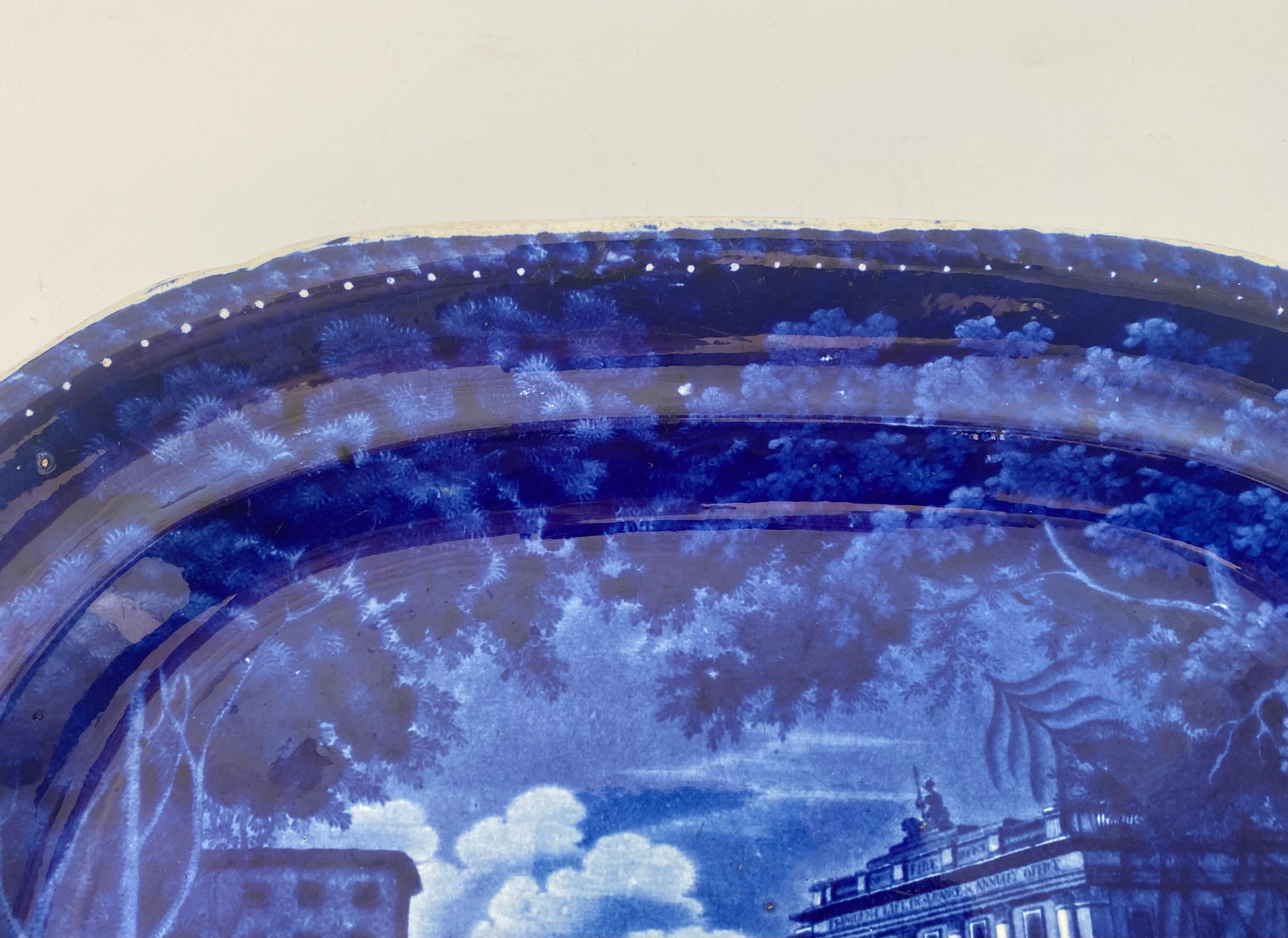 Staffordshire pottery meat plate, Adams Pottery c. 1830. Printed in underglaze blue, with a titled scene of ‘Regents Quadrant’, London. Showing a view of of figures and a dog, before the buildings along Regents Street. Framed by trees, and flowering