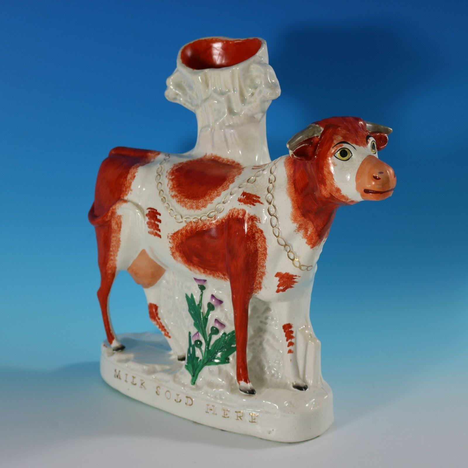 Staffordshire Pottery spill vase with a pastoral theme which features a cow, stood on an oval base. A thistle grows from under the cow. The piece is titled, 'MILK SOLD HERE'. Russet and white version. Dull gilt title and embellishment. Flatback,