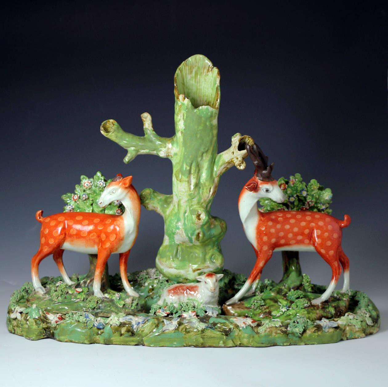 A rare and highly decorative Staffordshire pearlware tree trunk figure group.
The figures of the Doe and Stag with bocage are removable and sit on the large base which features the figure of a lamb. Figure groups of this size and complexity (16
