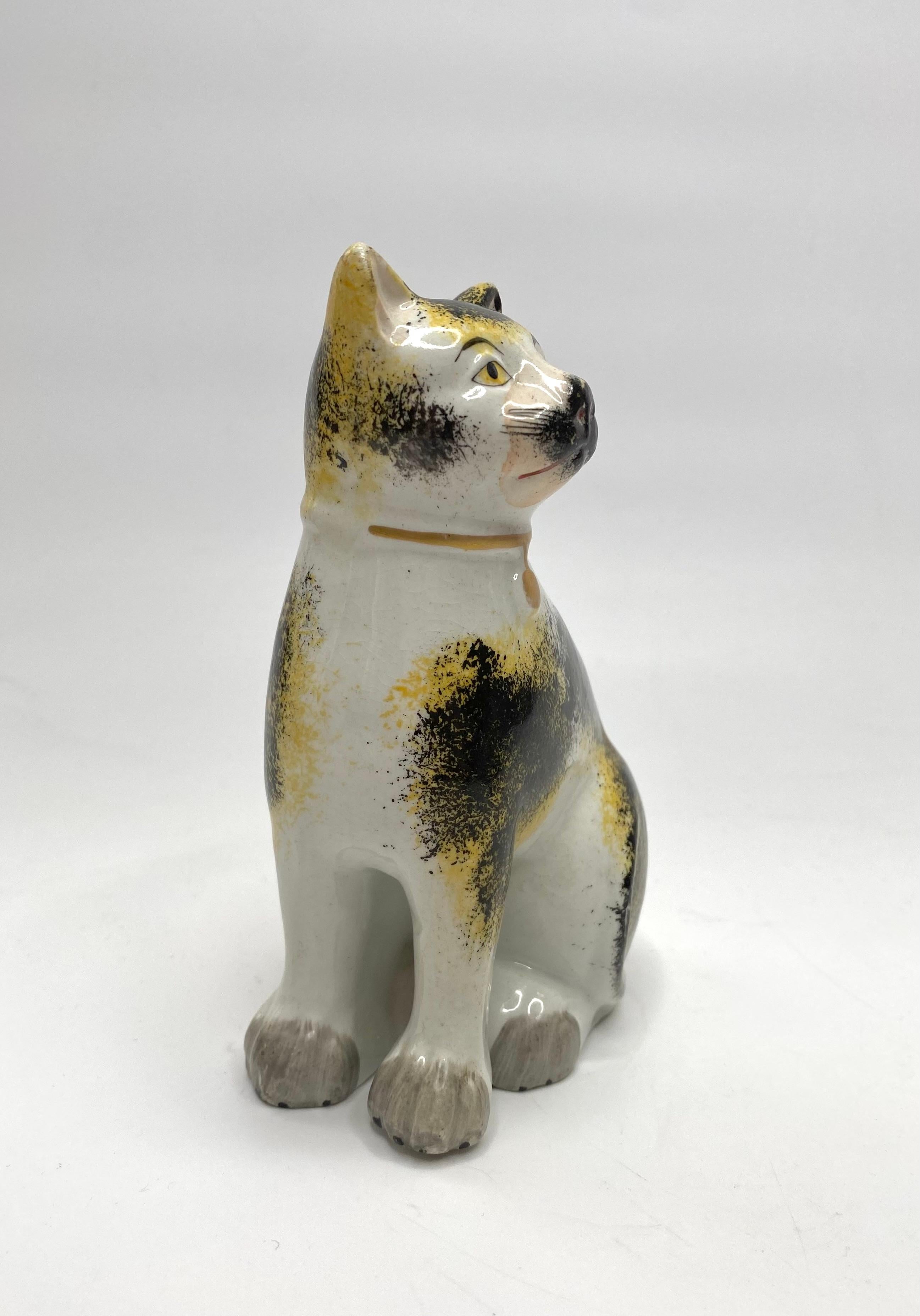 Staffordshire pottery seated cat, c. 1850. This finely potted cat, modelled in the round, and having a seperate front leg. He knows that he is a particularly good example, as he has an aloof expression on his face.
Decorated in underglaze yellow and