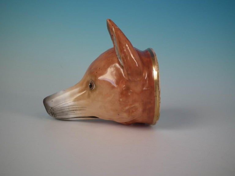 Staffordshire Pottery porcellaneous stirrup cup which features a fox head, stood directly on the ground, no base. Dull gilt base line. Decorated 'in the round' - decoration to front and reverse.