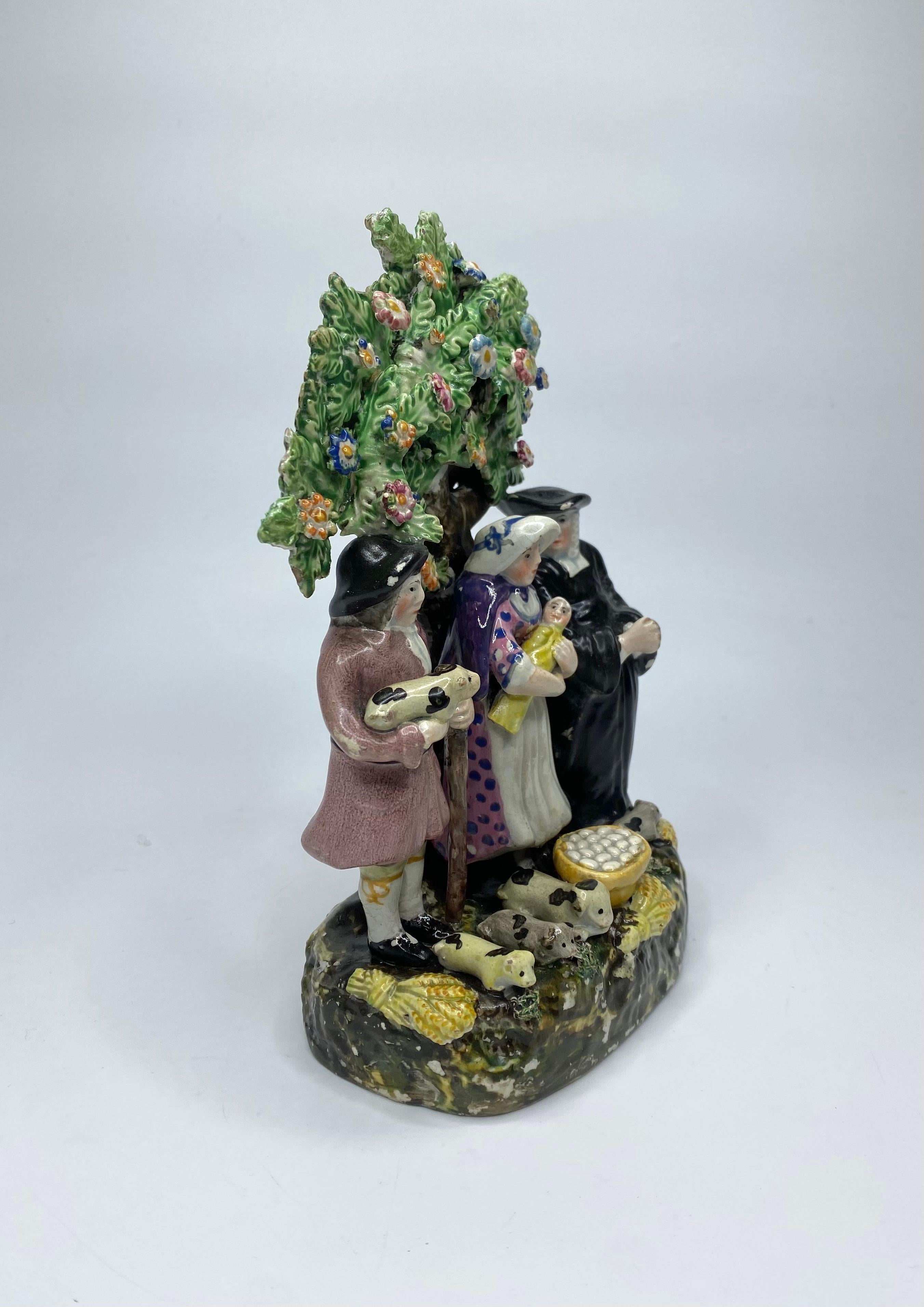 Staffordshire Töpferwaren 'Tithe Pig' Bocage-Gruppe, ca. 1830. Die drei Figuren sind so modelliert, dass sie vor einem Baum stehen. Der Bauer, der ein Schwein hält, seine Frau, die ihr Baby hält, und der Pfarrer, der ihnen mit betenden Händen