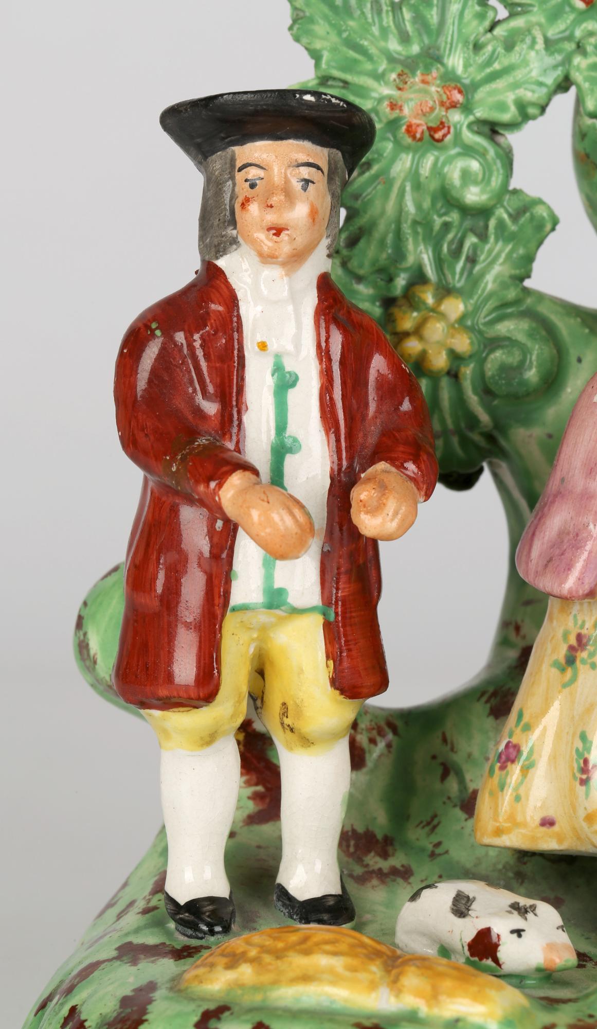 A fine antique English Staffordshire pearlware pottery tithe pig figure group dating to the early 19th century. The group stands on a raised oval shaped base and is mounted with a vicar, a farmer, the farmer’s wife with child the base strewn with a