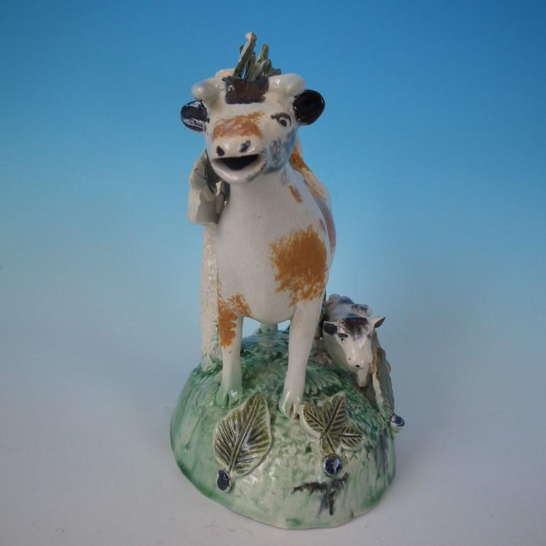 Tittensor (possibly) Staffordshire Pottery Prattware bocage cow creamer which features a cow and a calf, recumbent on a shaped base. Decorated 'in the round', decoration to front and reverse.