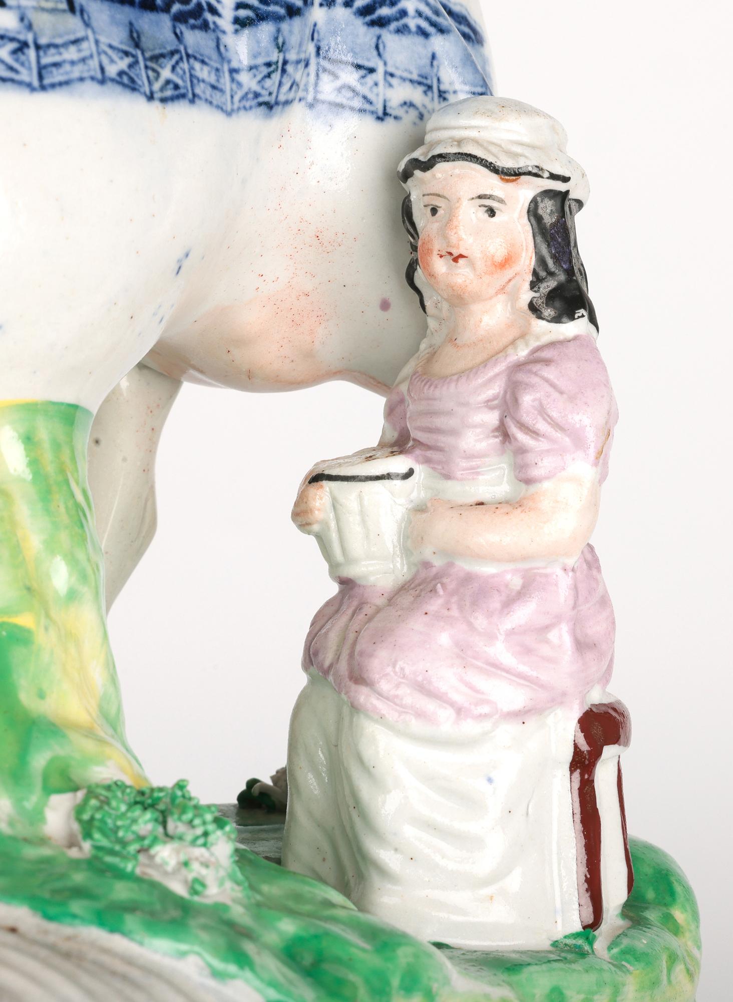 A rare and stunning antique Staffordshire transfer printed pottery model of a cow and milkmaid figure dating from the mid 19th century. The well potted and hand crafted figure stands raised on  an oval shaped base with a large standing cow with a
