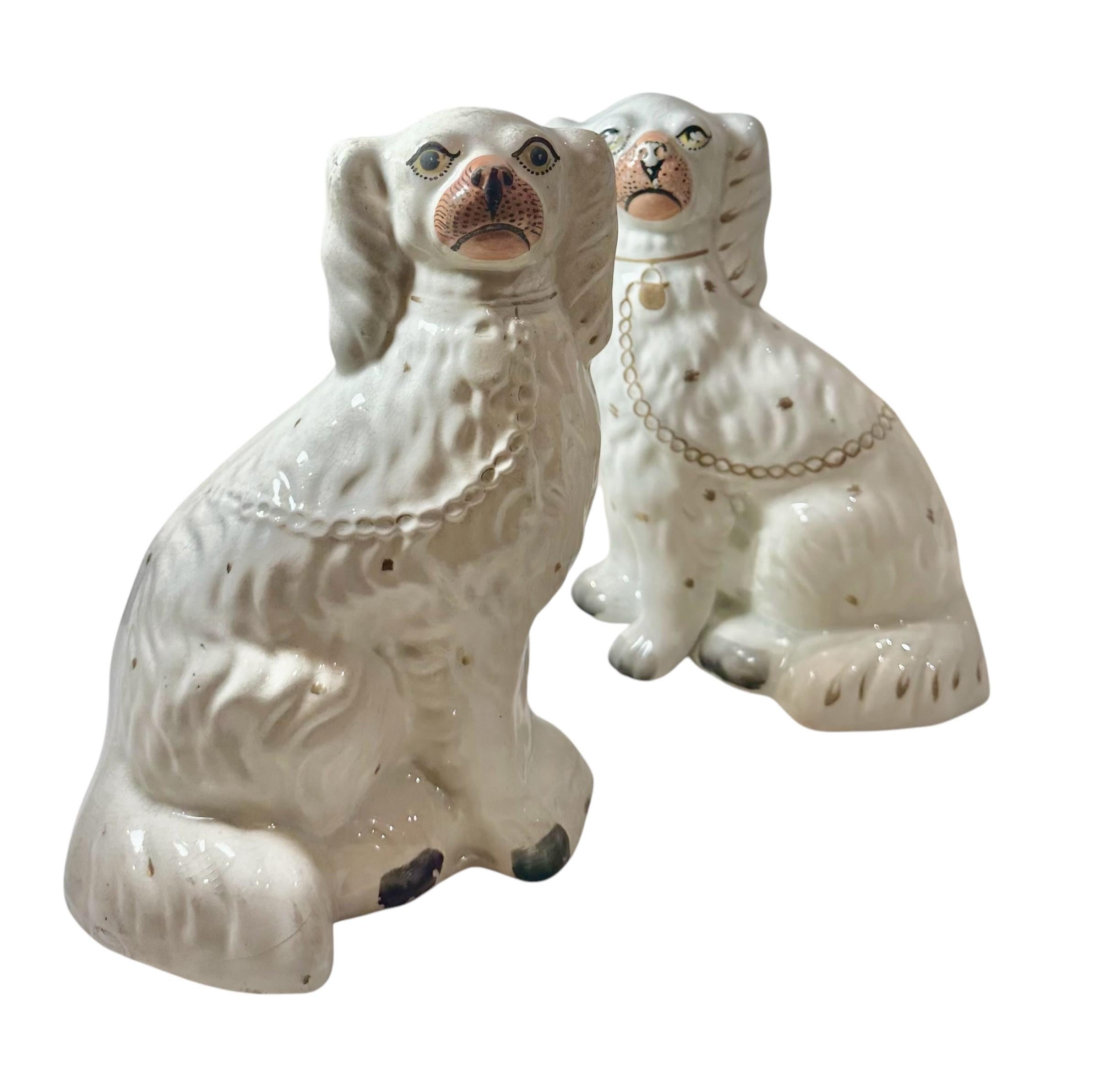 A charming pair of victorian era Staffordshire porcelain Spaniels. These beloved 19th century mantel dogs feature finely painted details and classic gilt accents. One Spaniel shows some wear to the face, but both remain in very good condition for