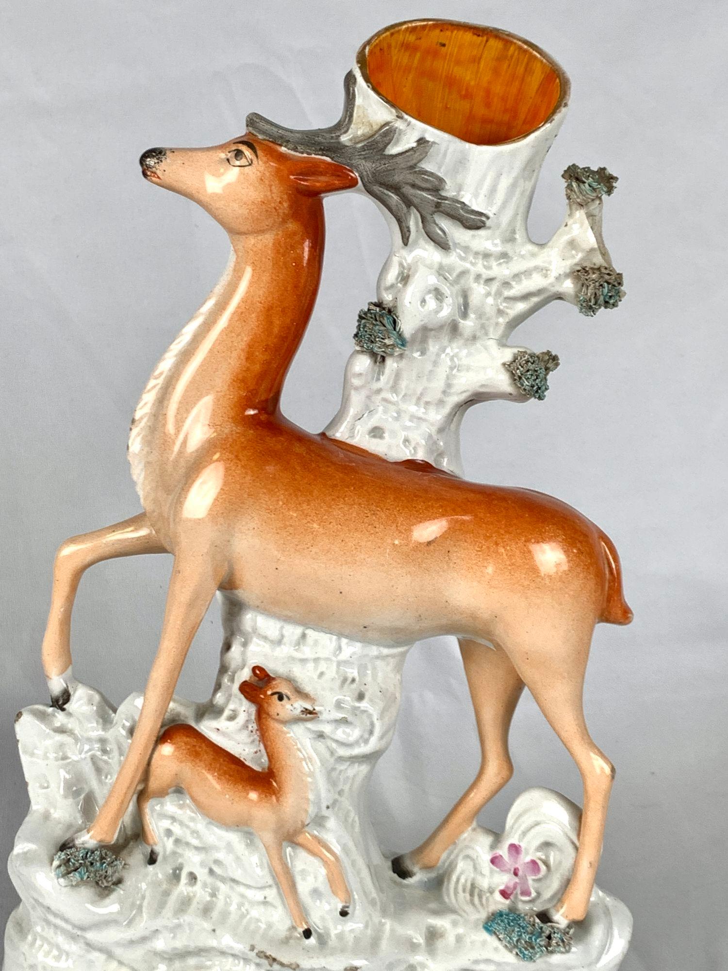 Questo grande vaso di Staffordshire presenta un fiero cervo con un cerbiatto su una base sagomata.
I cervi sono dipinti in arancione/marrone naturalistico.
Il bordo superiore del tronco dell'albero è dorato e la base bianca presenta una sottile