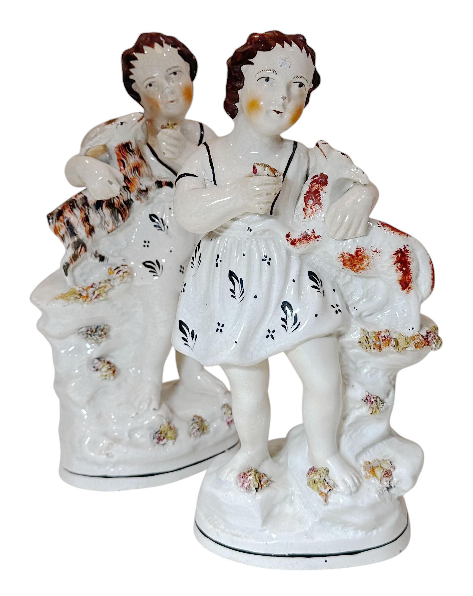 A pair of Staffordshire statues children holding goats. Circa 1890s, England.