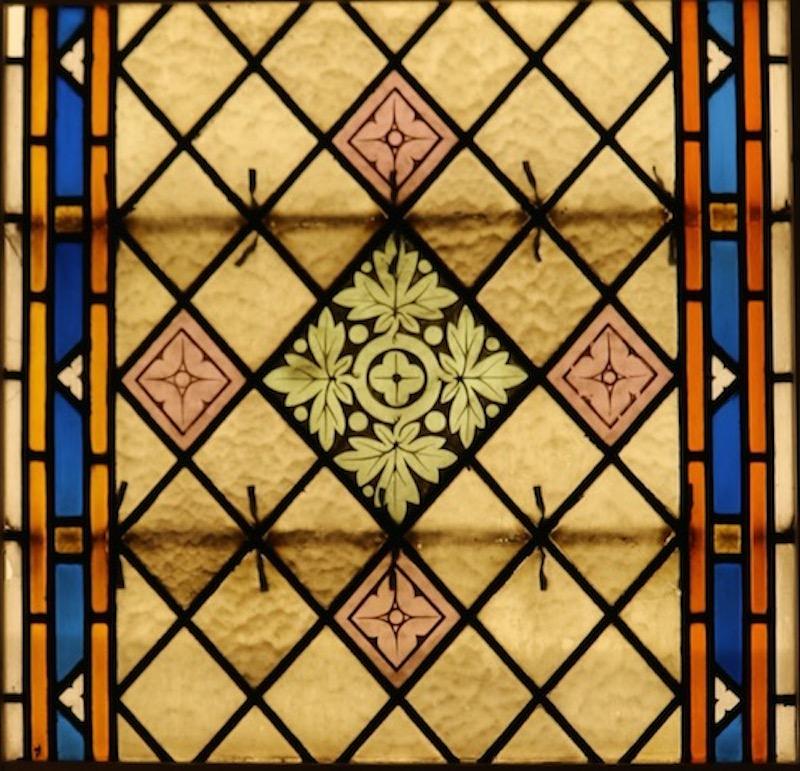 A stained glass church window consisting of three pieces, housed in temporary pine frames.