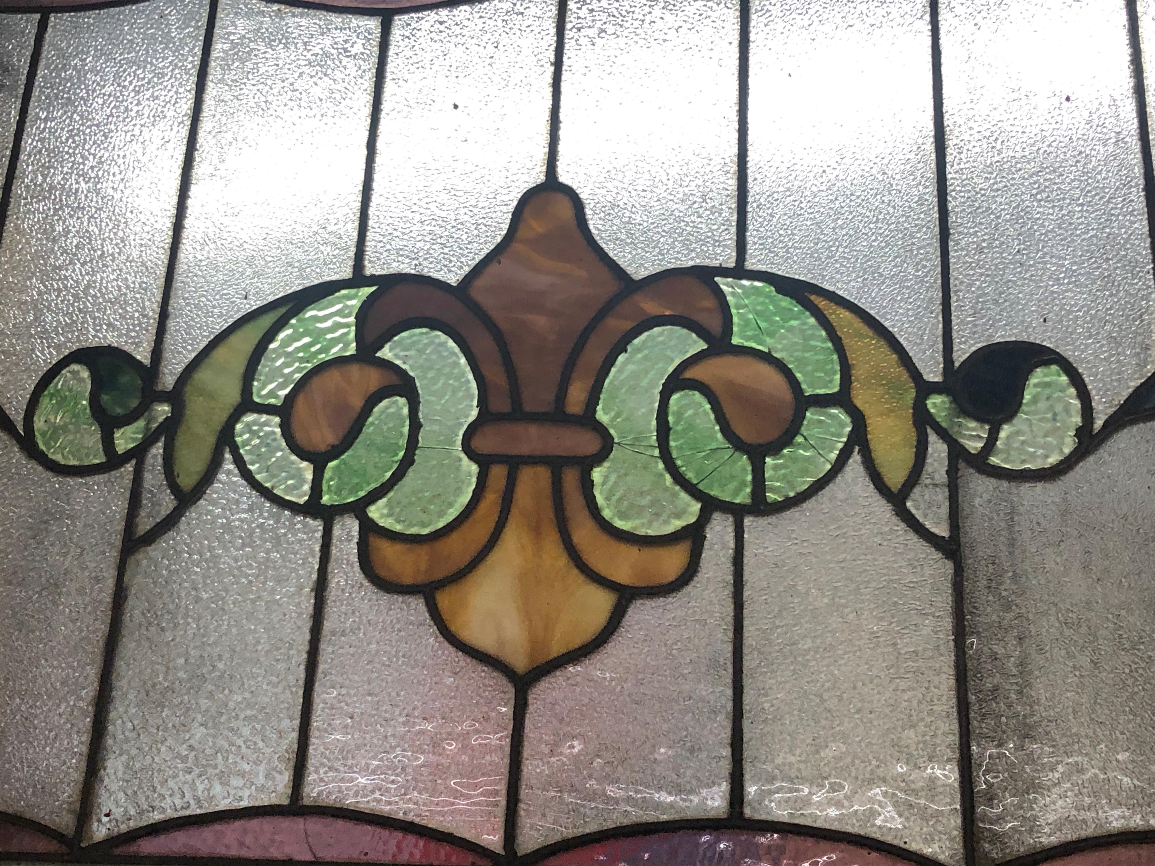 Fenêtre du début du siècle de fabrication américaine avec motif Fleur de lys en vitrail. 
Le vitrail est actuellement placé dans un cadre temporaire en bois - les dimensions totales sont celles du vitrail et du cadre.
Situé à NY