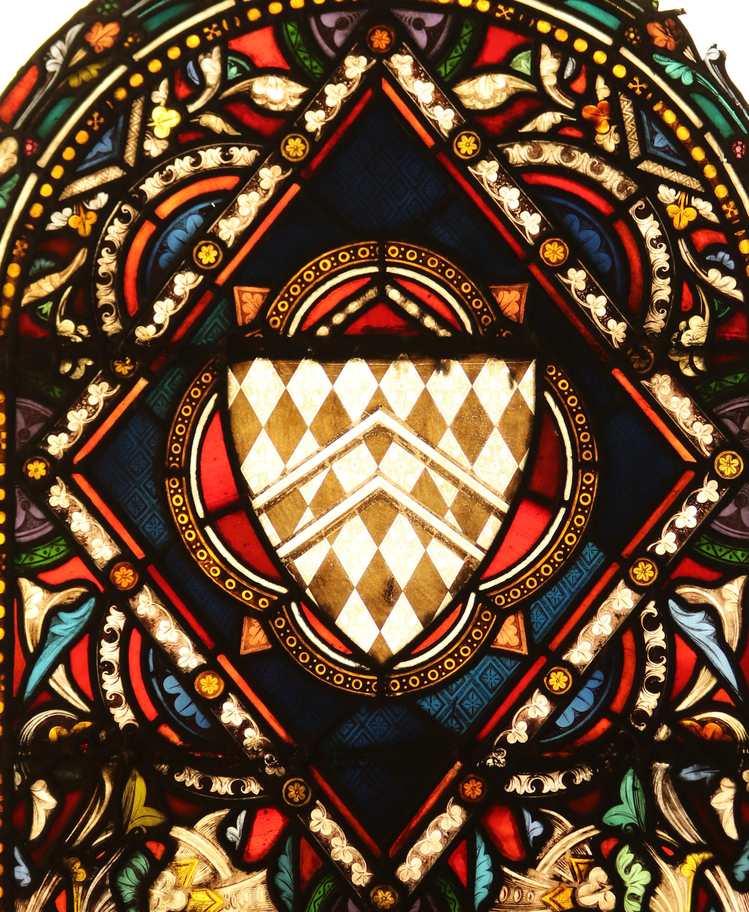 A reclaimed arched stained glass window with a central shield crest.