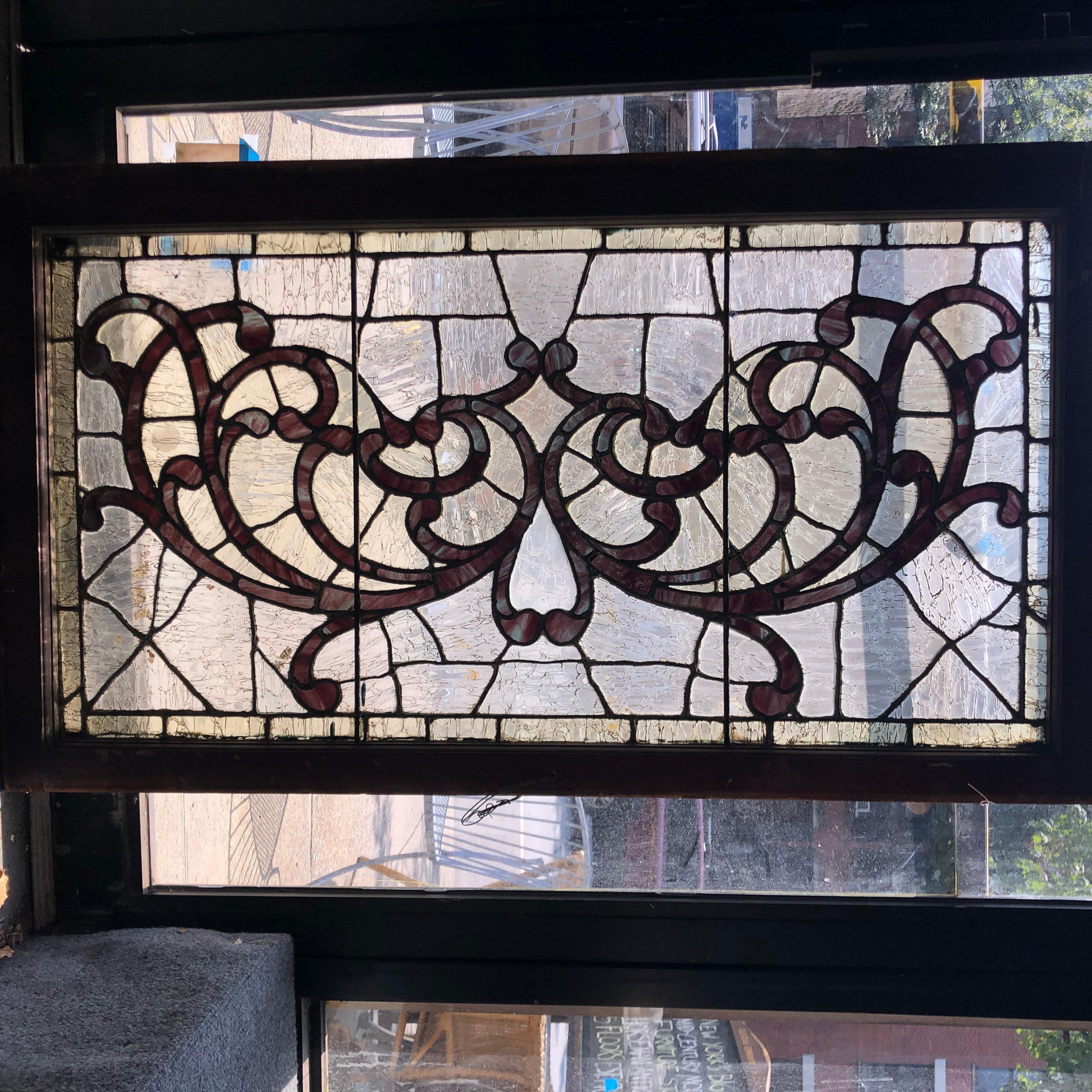 Art Nouveau style window with crackle texture clear glass and a wonderful design of purple colored glass. This transom window will dress up your door and stand out in the neighborhood!
Currently housed in a wooden frame - the overall dimensions are