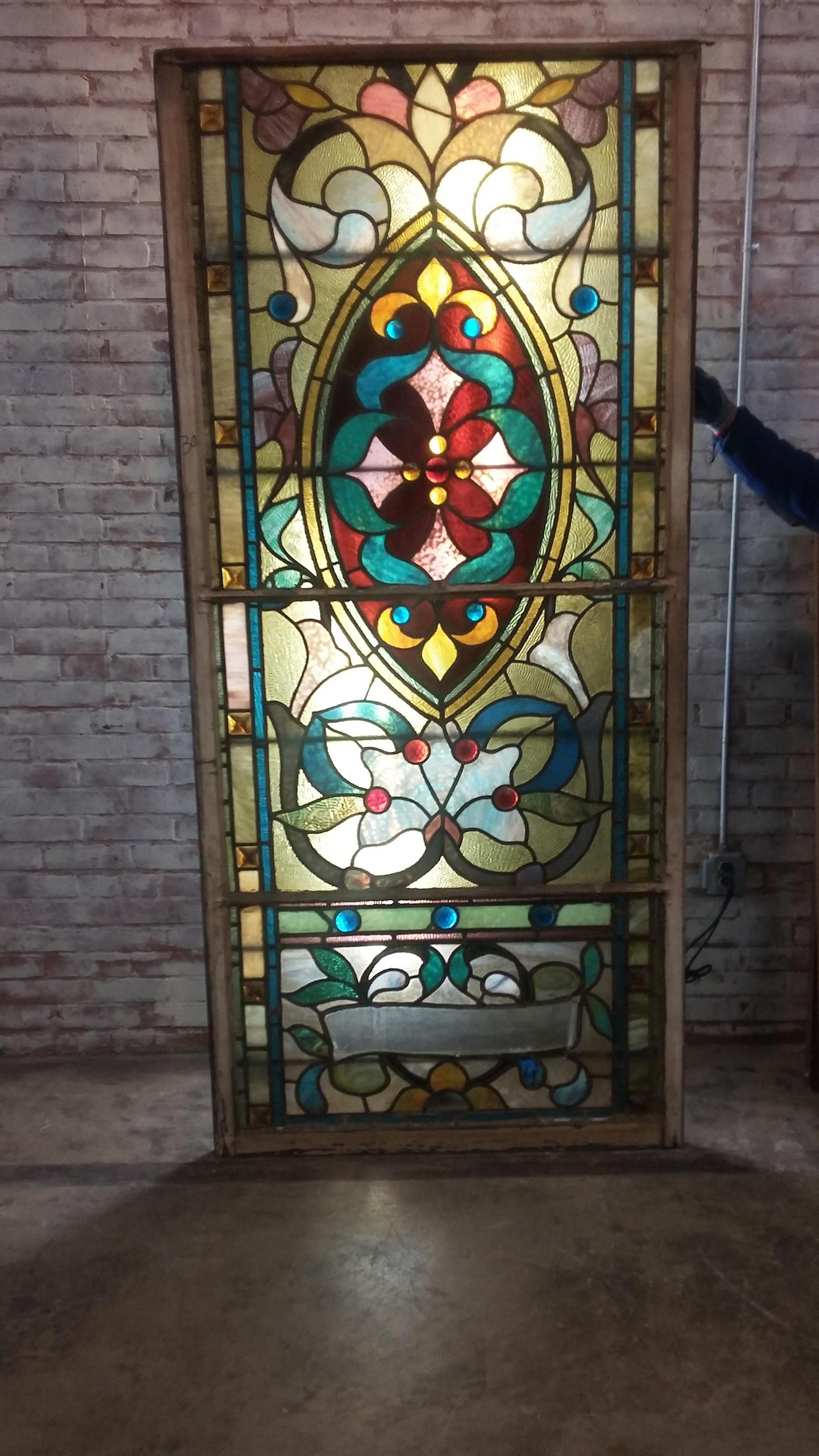 Beautiful 19th century stained-glass window. Divided into 3 sections in original frame. Very uniquely made with multiple colored glass. Adorned with 17 pieces of jeweled glass. Along each side of the frame there are 16 chunk
pieces. Condition is
