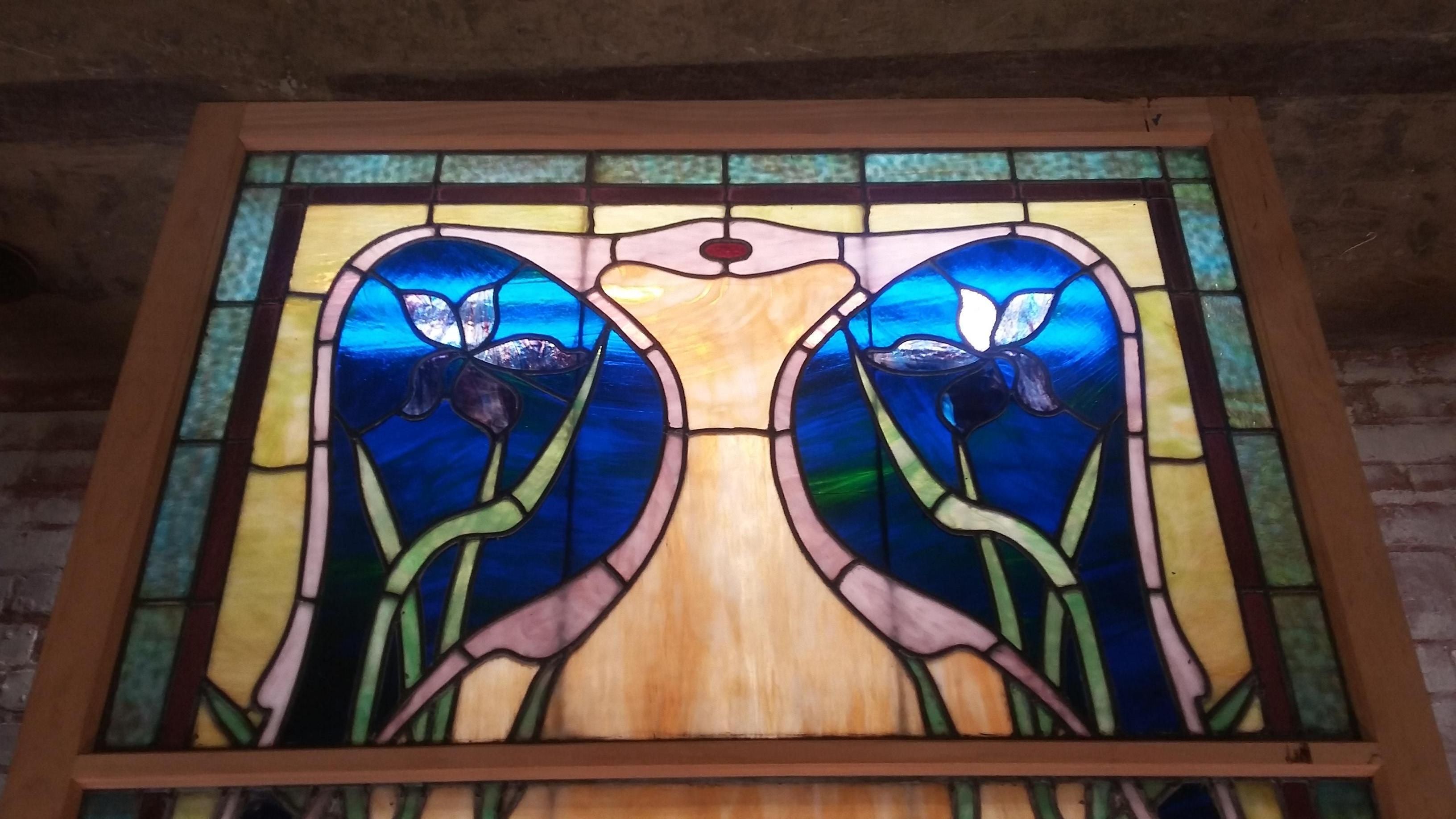 Beautiful vintage 19th century stained-glass window. Original window but has been reframed. An usual style Art Nouveau with multiple colored glass (blue, green, amber) and wonderful floral motif.. Original window is 2 sections but it has been