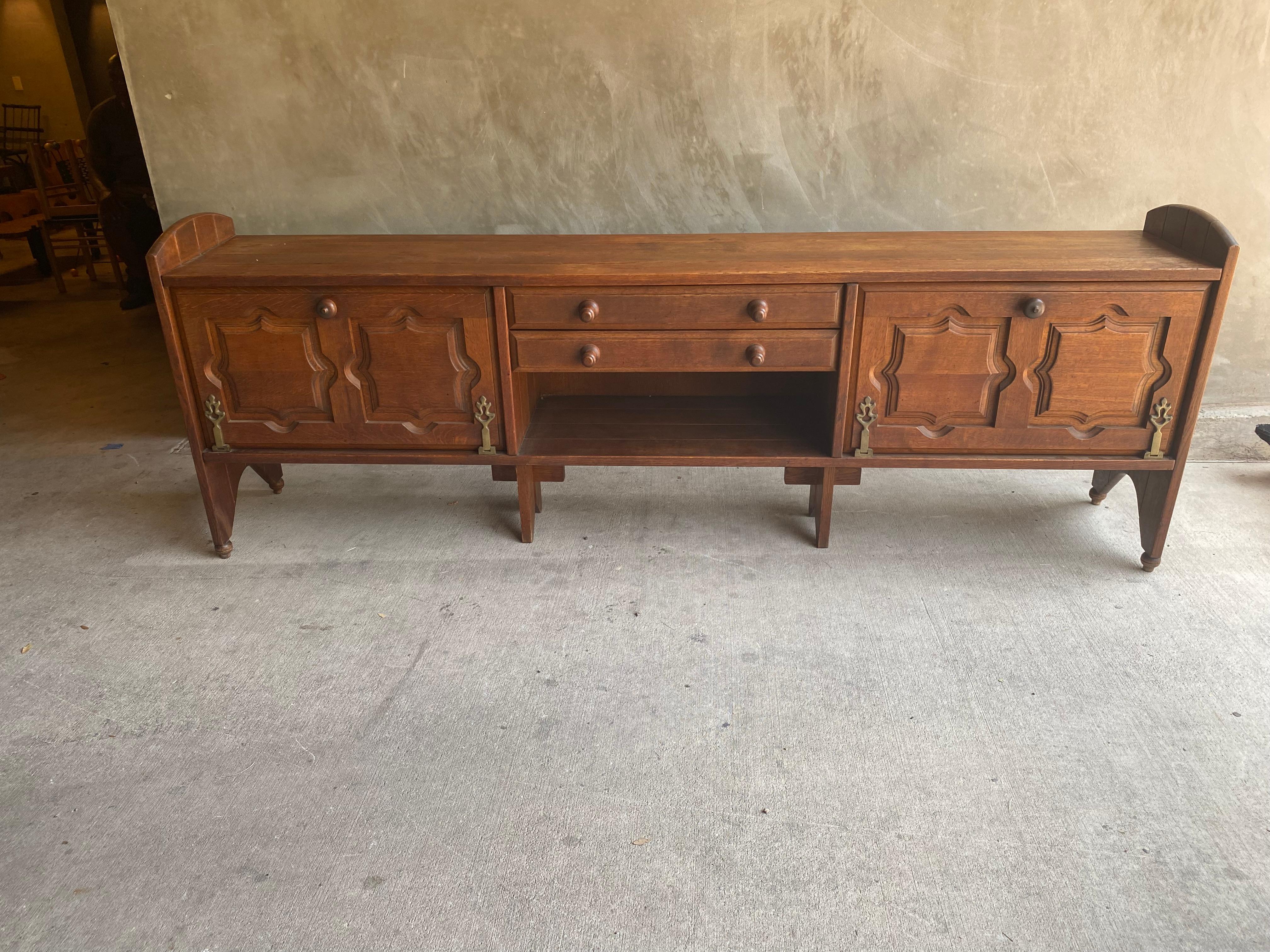 A unique and early piece by midcentury French designers Robert Guillerme and Jacques Chambron. Solid French oak sideboard with drop down compartments and drawer storage. The custom designed hinges and pulls are representative of the whimsey often