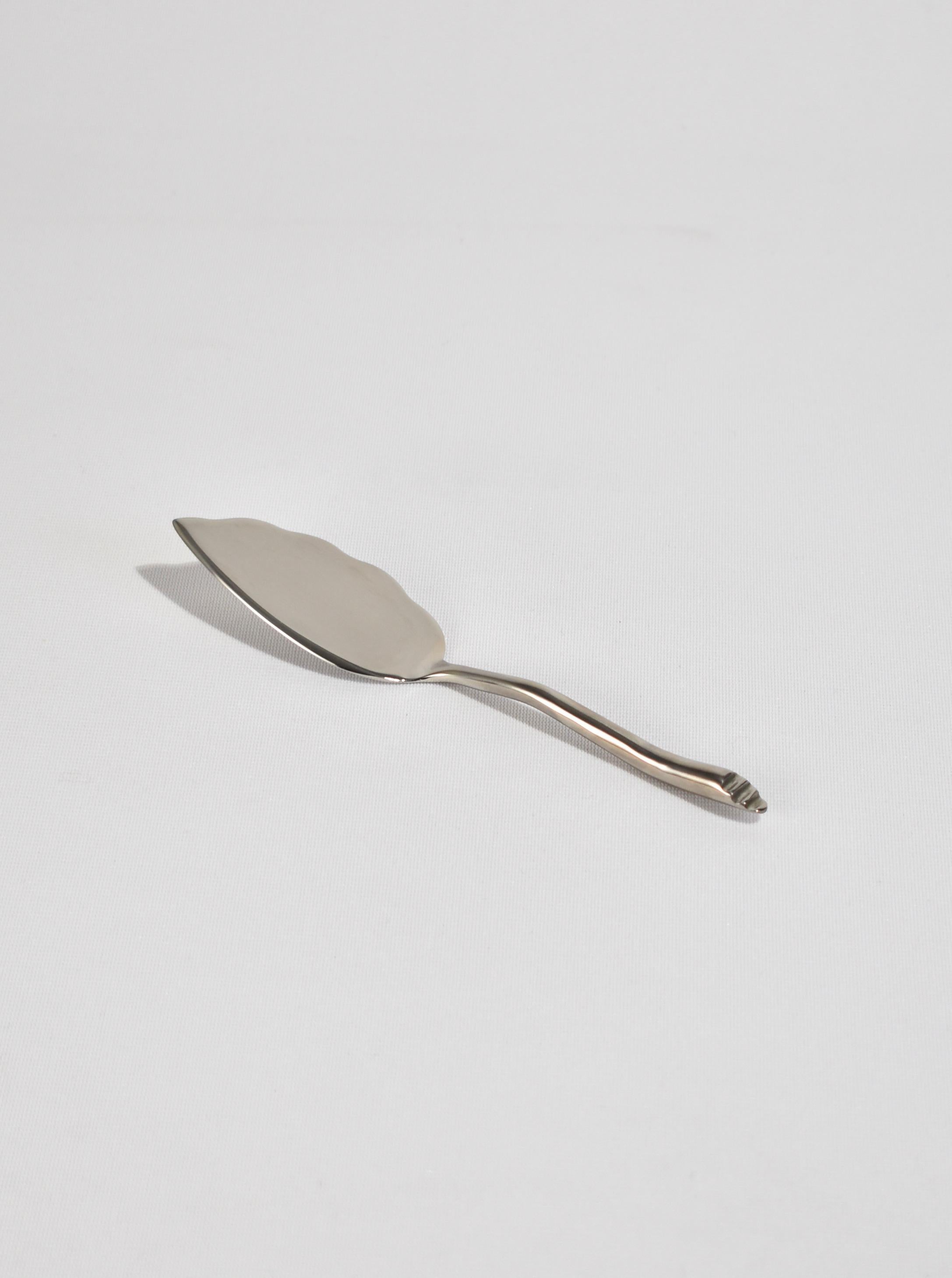Beautiful, silver-plated cheese server in the 'Shore' pattern. Each piece is hand-forged and features an undulating handle with angled end. Impressed above end 'IZABEL LAM'.

Designed in the late 1980s by Izabel Lam.