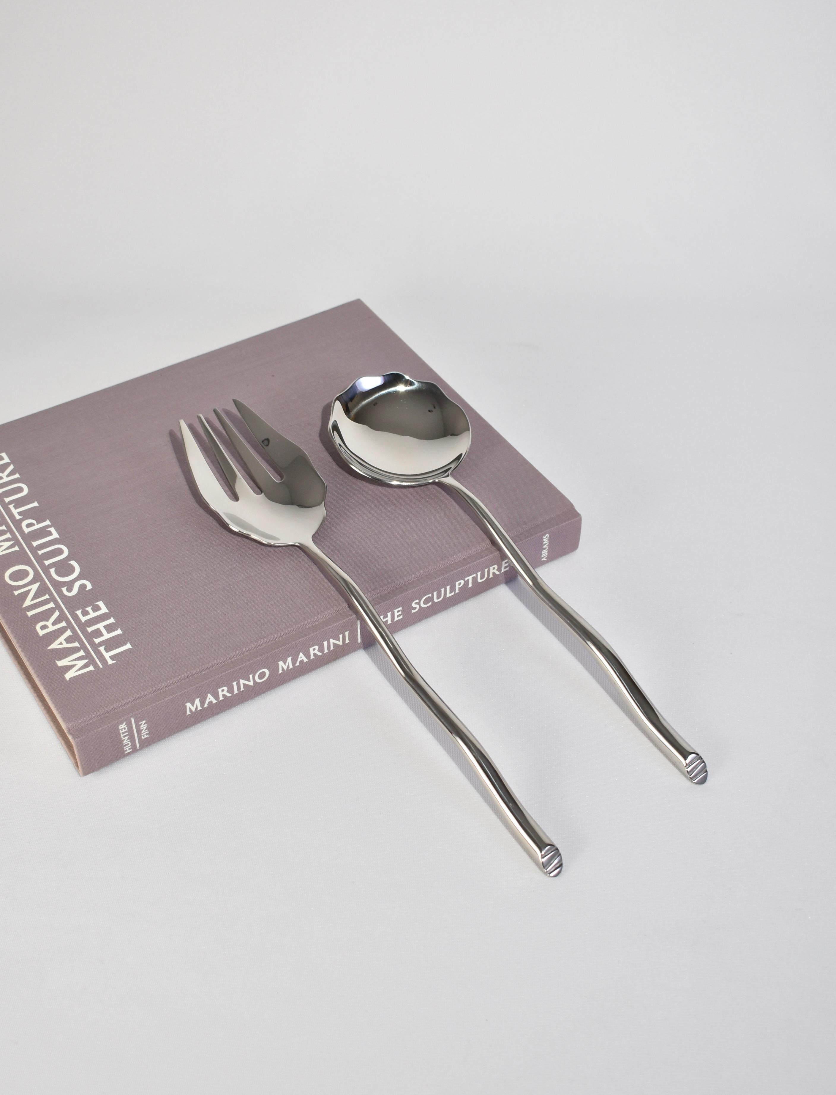 Sculptural, large stainless steel salad serving set in the 'Shore pattern'. Each piece features an undulating handle with an angled end. Impressed above end on handle: 'IZABEL LAM'. 

Designed in the late 1980s by Izabel Lam

Dimensions: