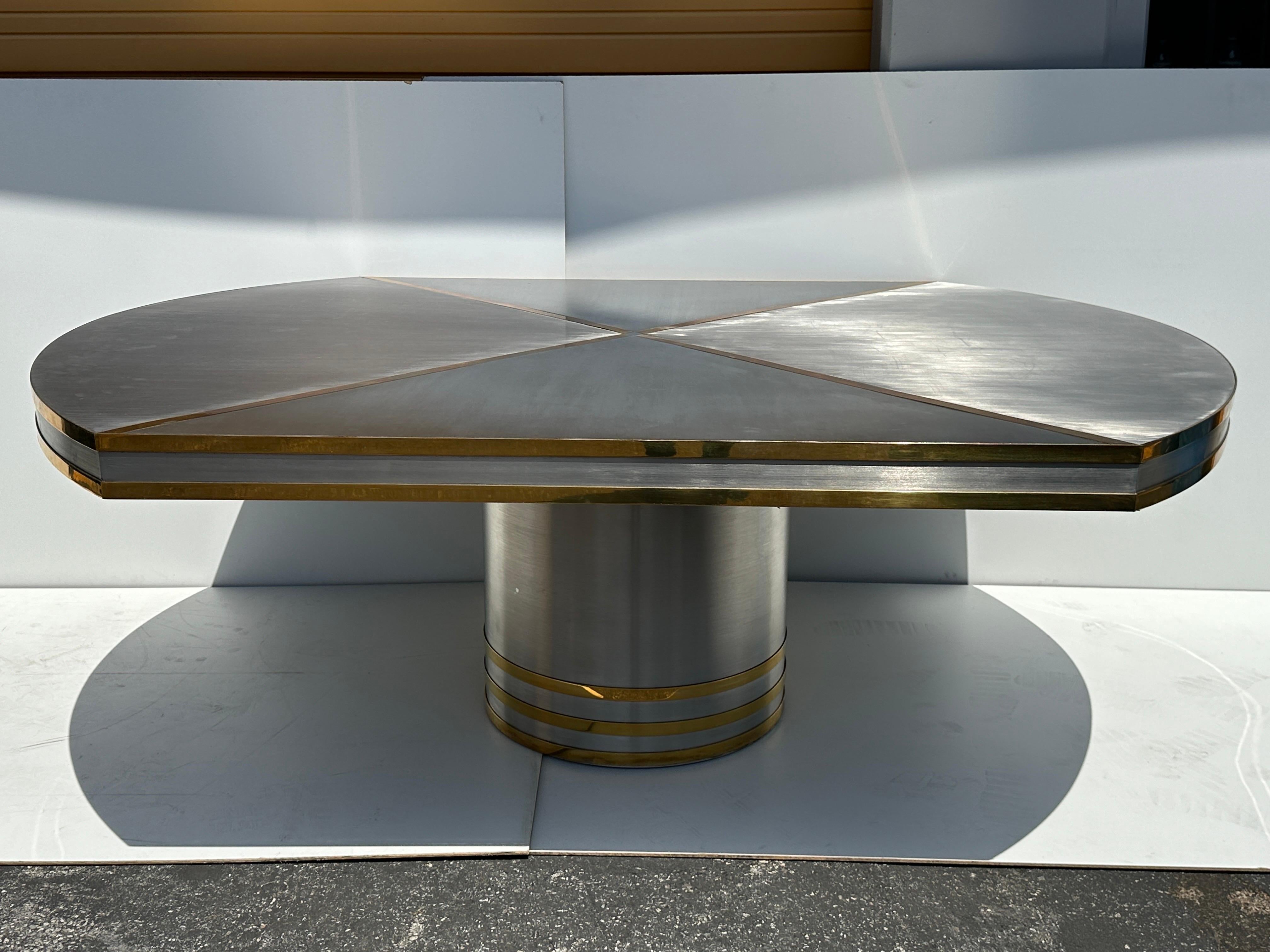 Brushed stainless steel and brass dining table attributed to Karl Springer or John Vesey.
Table top is set on a 24” diameter base with gilt brass stripes. This table is really glamorous, it is really hard to capture real beauty on camera.