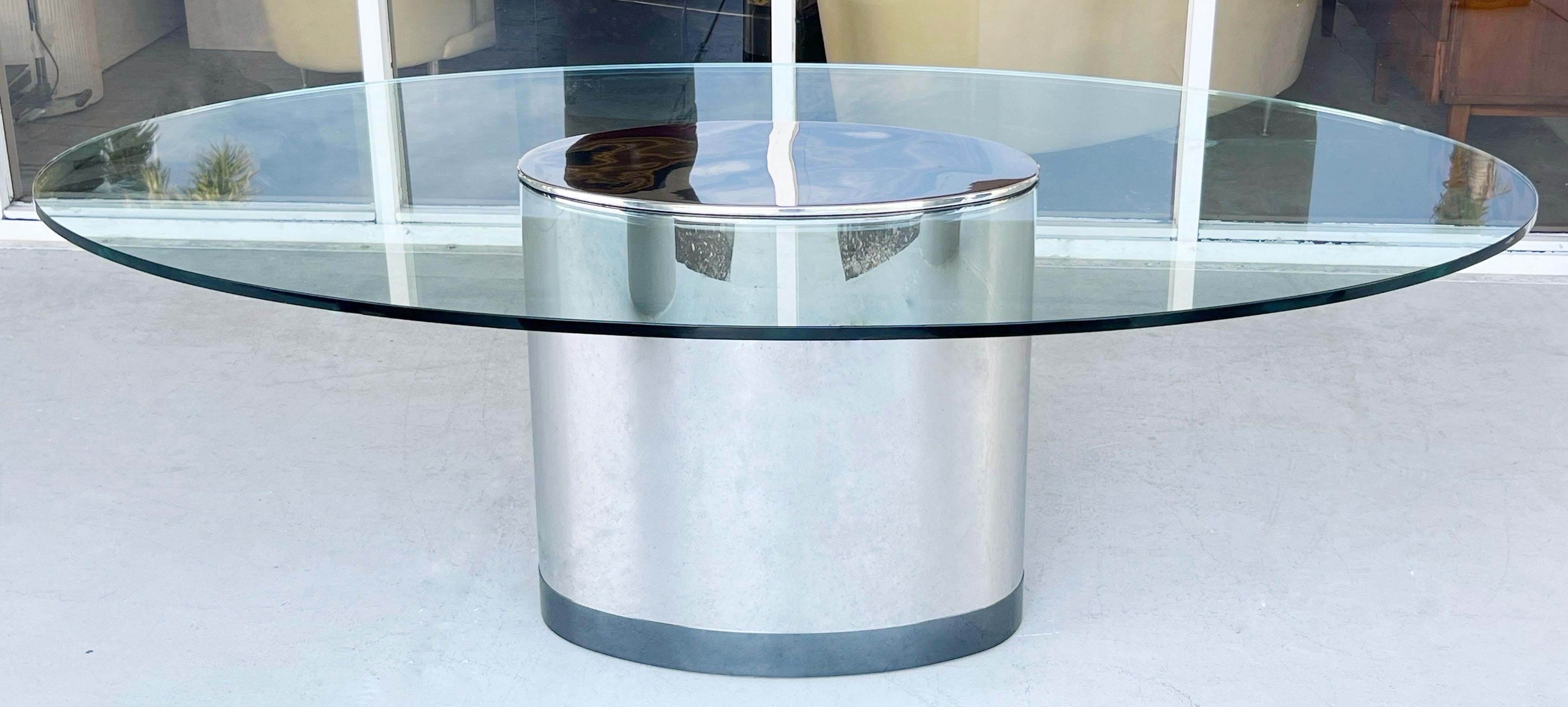 Une table spectaculaire. Piédestal ovale en acier poli avec une rayure gunmetal à la base. 