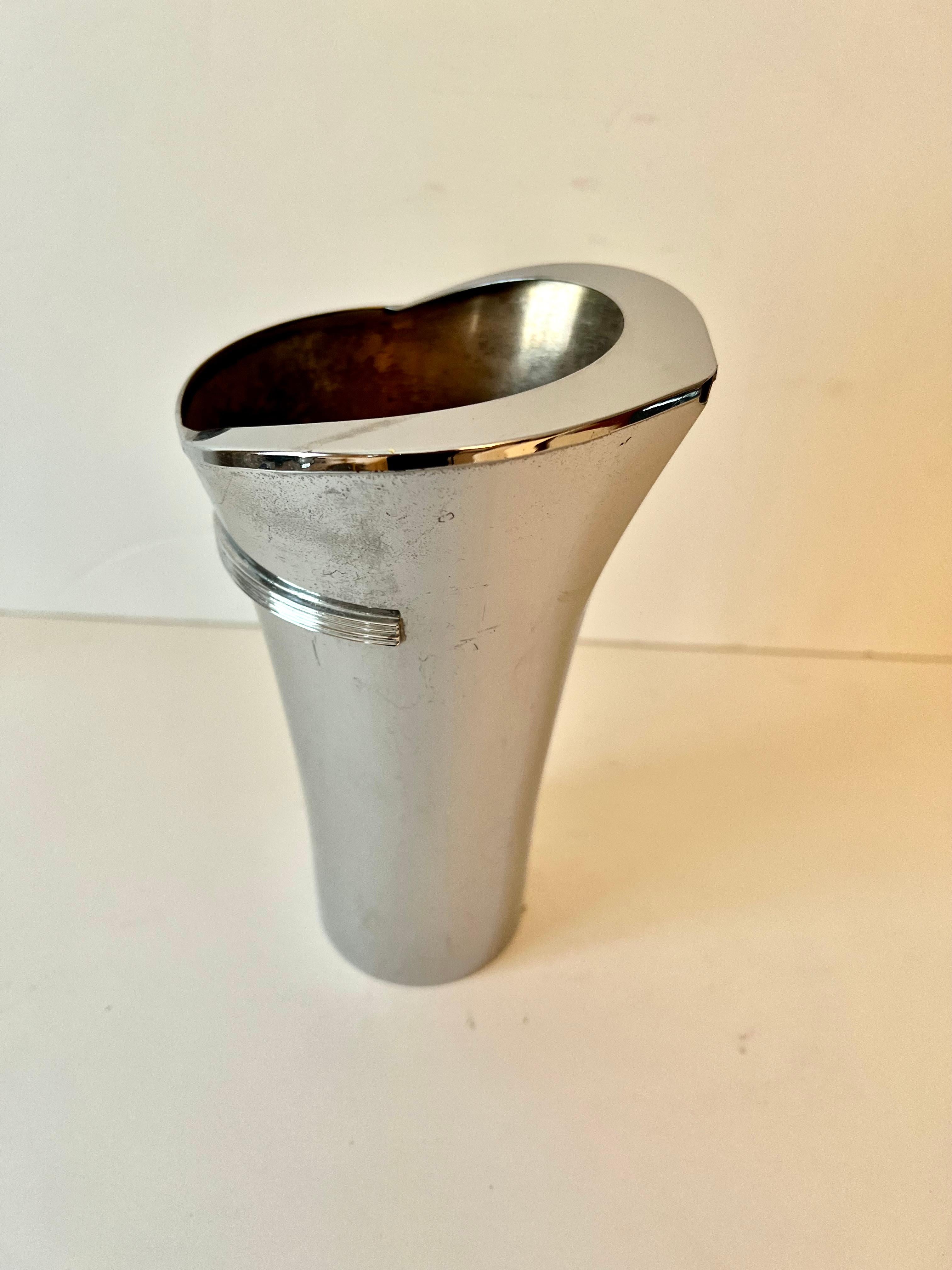 A Stainless Steel Cocktail pourer.  The piece has a uniquely designed head that comes to a point and the addition of several decorative lines / ribs, making it easier to hold and also give it an art deco flavor.

The mid century piece is in