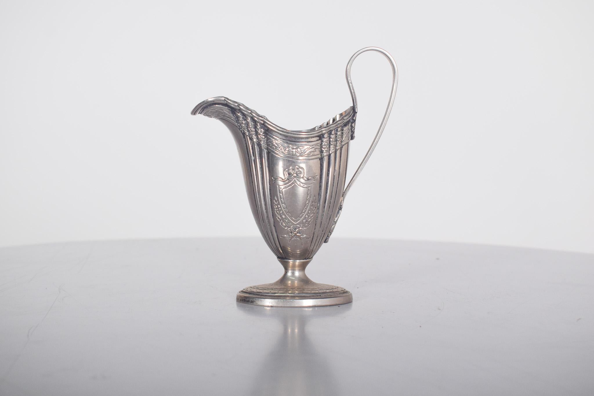 Salsera de acero inoxidable. Con un cuerpo alargado y curvado y una base circular ligeramente elevada, proporciona estabilidad y un toque refinado. Los laterales están decorados con finas estrías verticales y delicados relieves florales, que