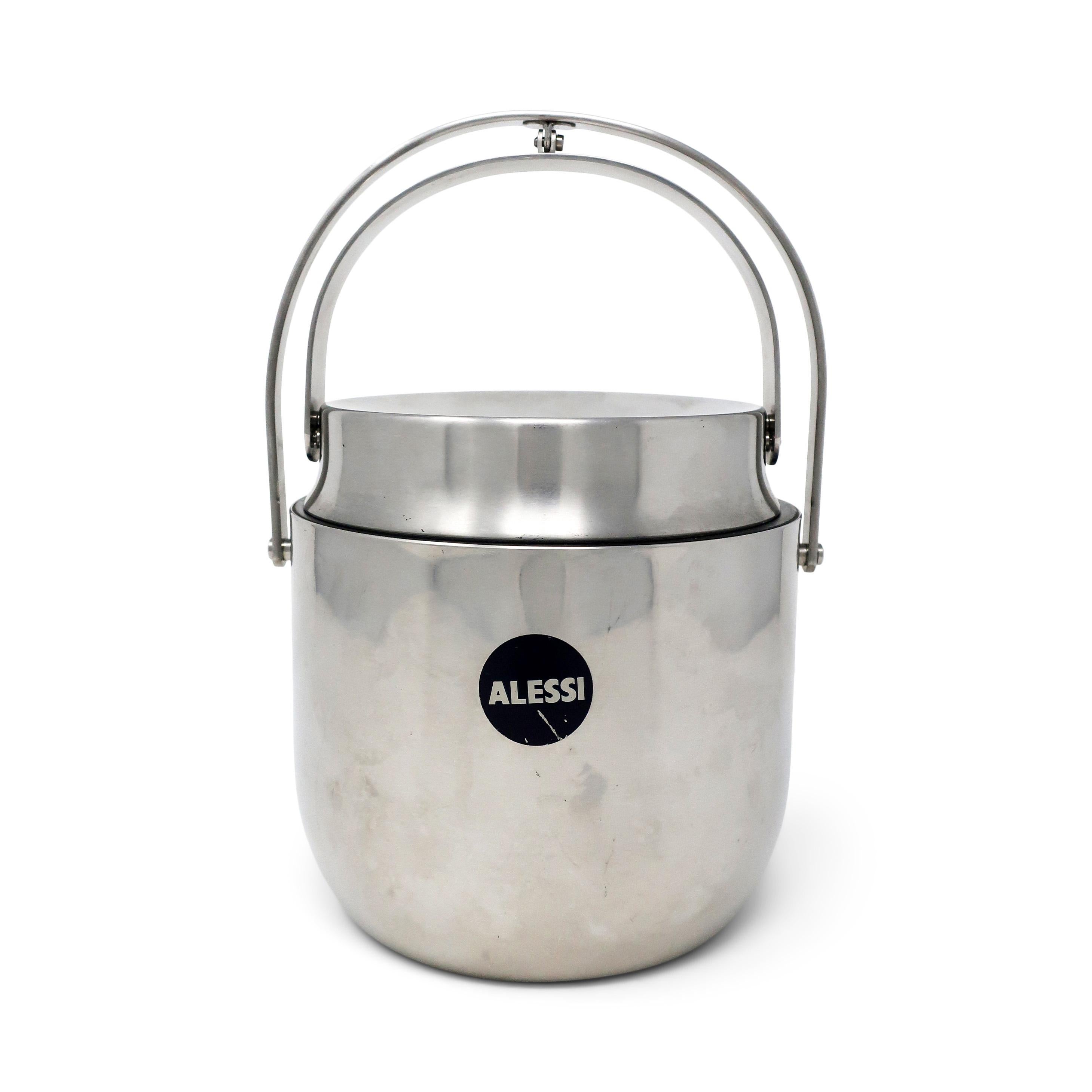 Un seau à glace en acier inoxydable rarement vu avec un ingénieux couvercle mécanique conçu par Anselmo Vitale et Carlo Mazzeri pour Alessi en 1971. Fabriqué en Italie en acier inoxydable 18/16 avec un revêtement plastique amovible avec des trous de