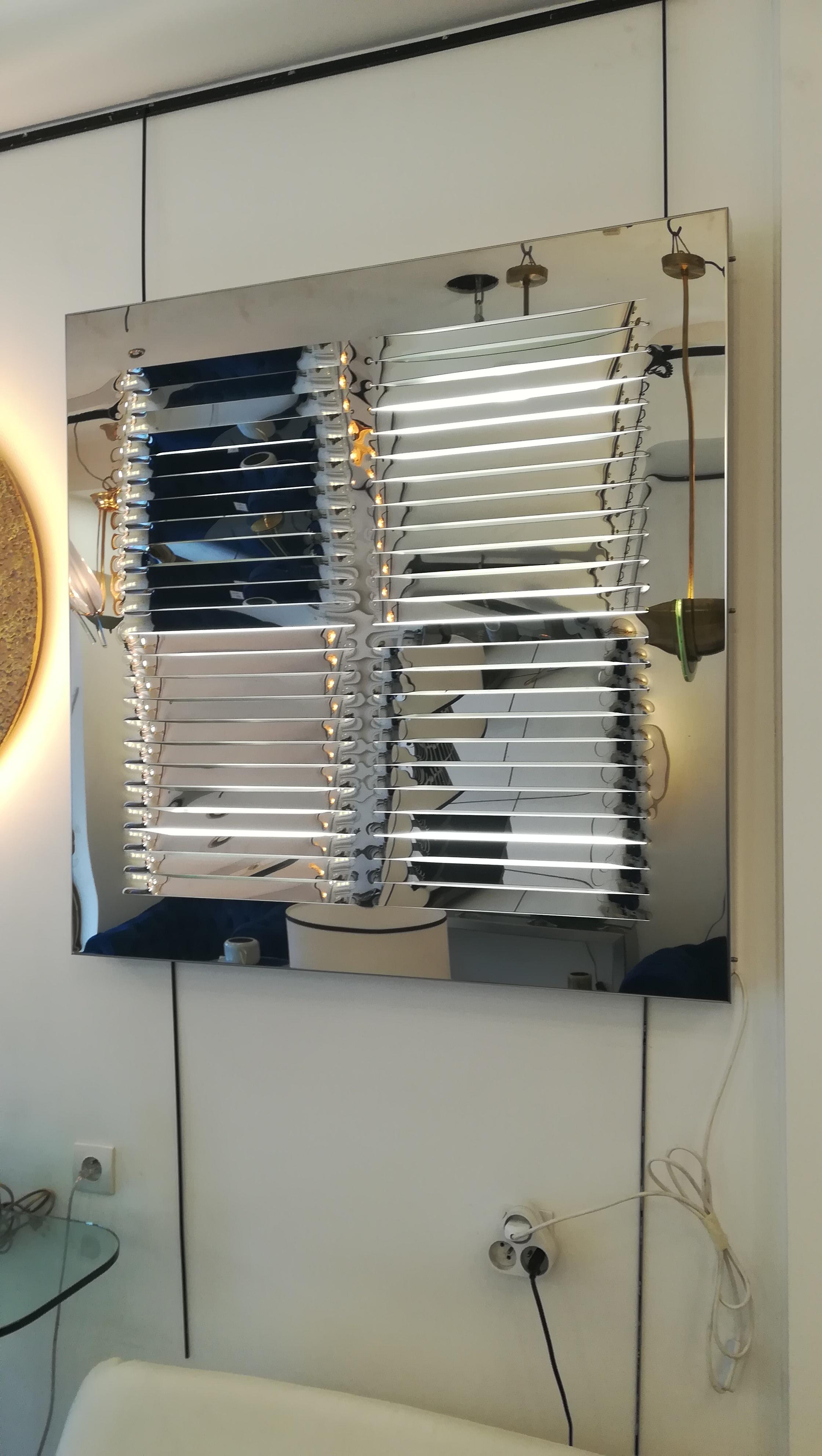 Stainless steel kinetic sconce with 3 white neons lights.
Horizontal cuts.