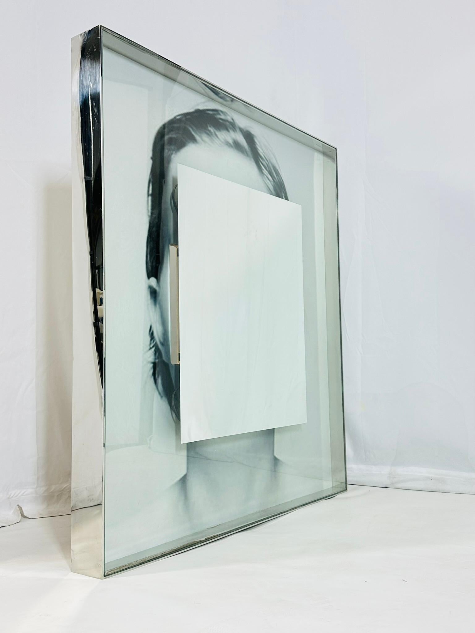 Large wall mirror made in Italy and designed by Philippe Starck for the SLS hotel in Beverly Hills.

 The mirror frame is thick stainless steel, the mirror lights up to show the image behind the mirror. 

The piece is in used condition with some