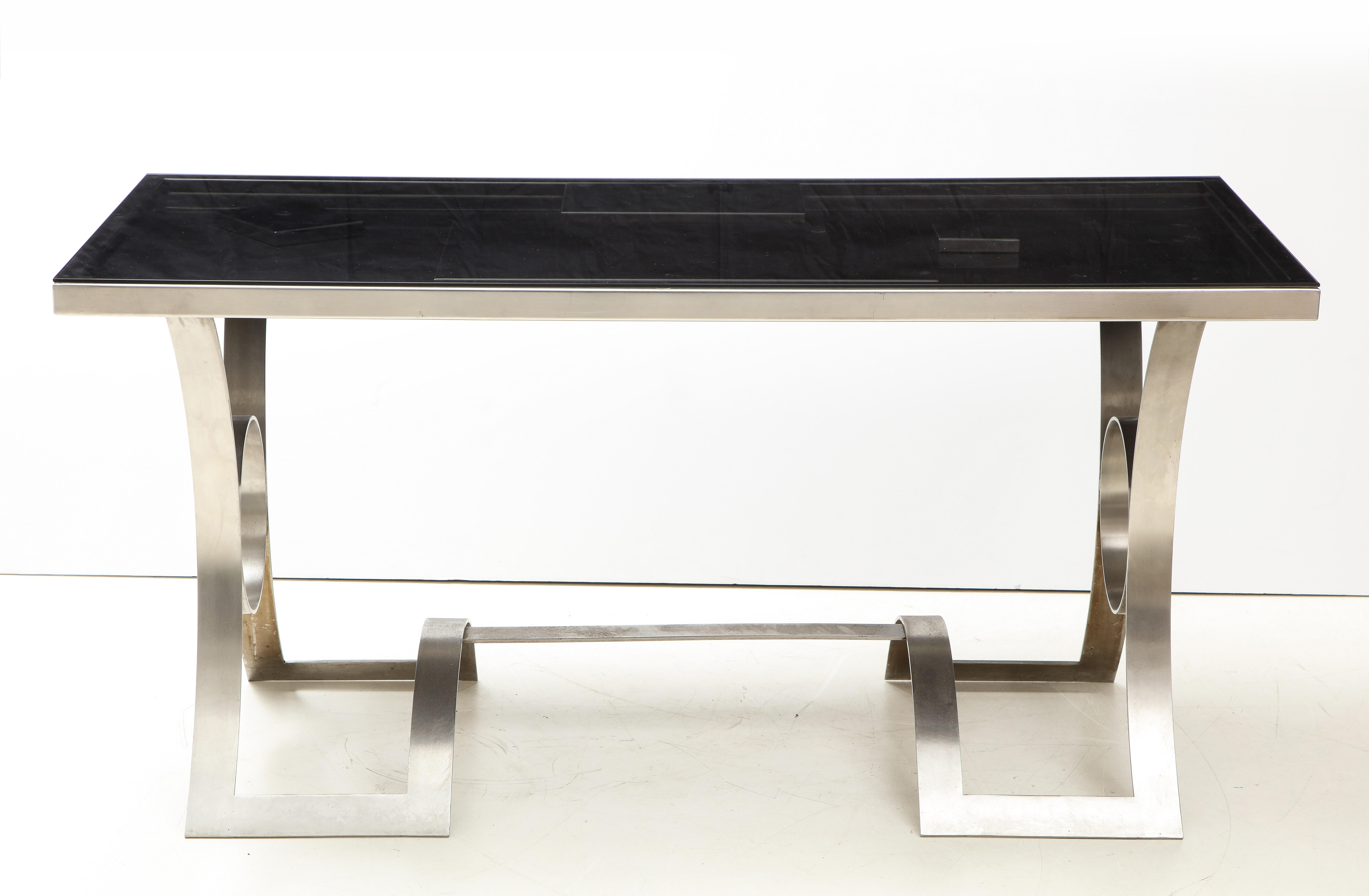 Rare Stainless Steel Desk with Smoked Grey Glass Top, France, c. 1970

This exquisite table sports an undulating, curvilinear base with a custom glass top in a smoked grey finish. 

The last three images picture the surface of the table beneath the