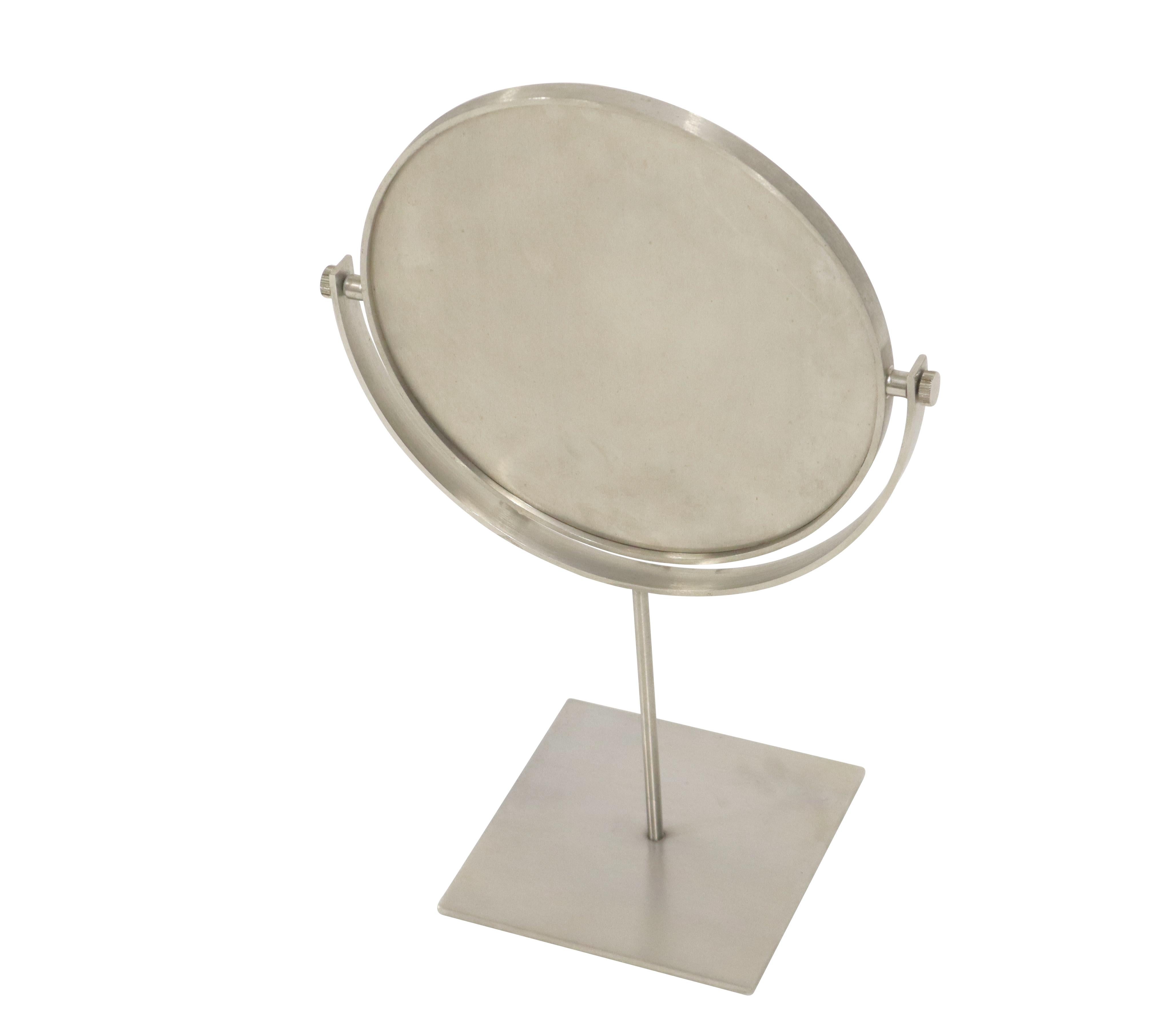 Vanity mirror with brushed stainless steel frame. Tabletop mirror sits in swivel support base. One side is mirror, other side full brushed stainless disc.