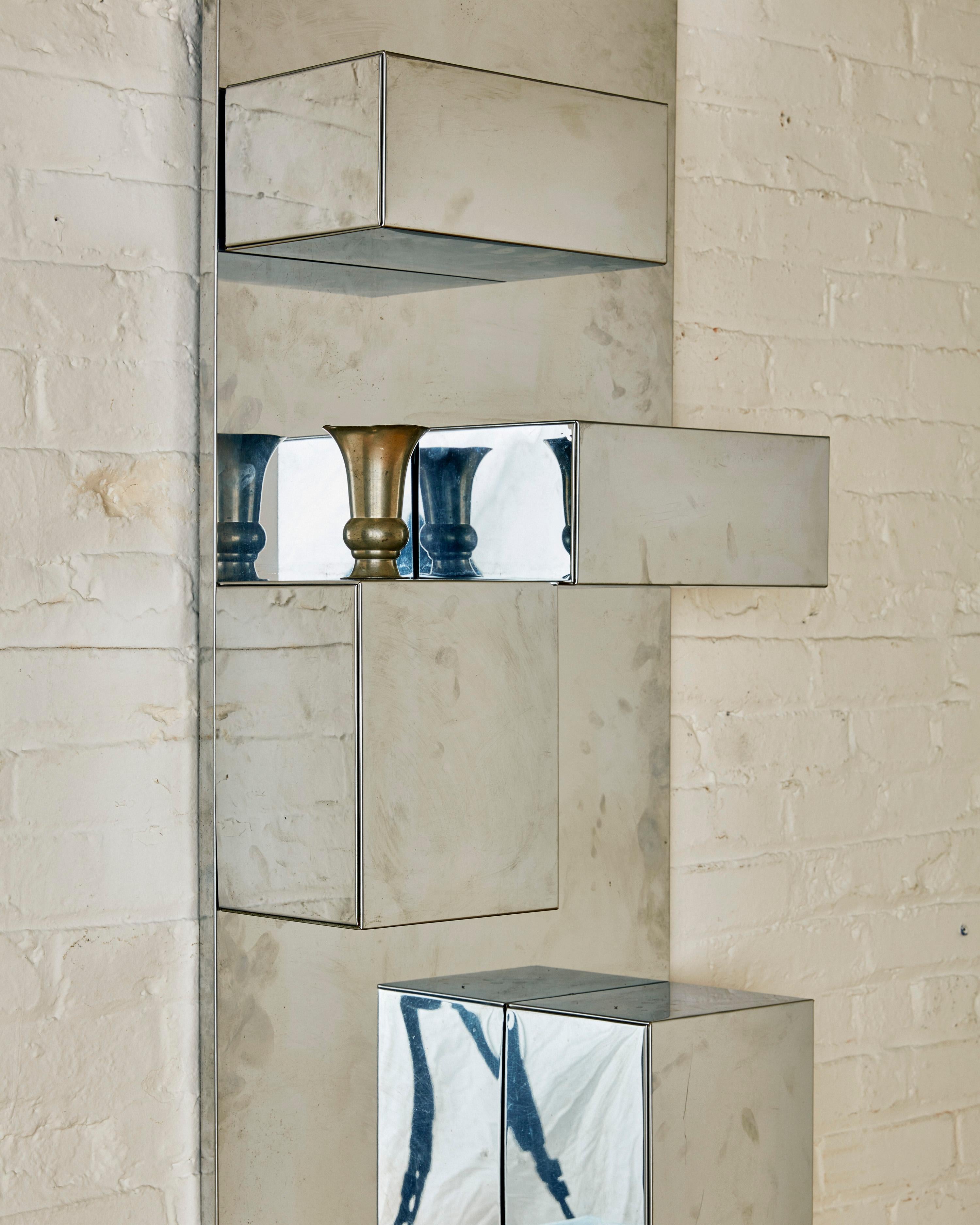 Stainless Steel Wall Shelf by Milo Baughman C. 1970. This shelving unit is extremely well crafted with seven removable box shelves and a back wall panel that is made of wood covered in stainless steel, making this item durable and built to last.

