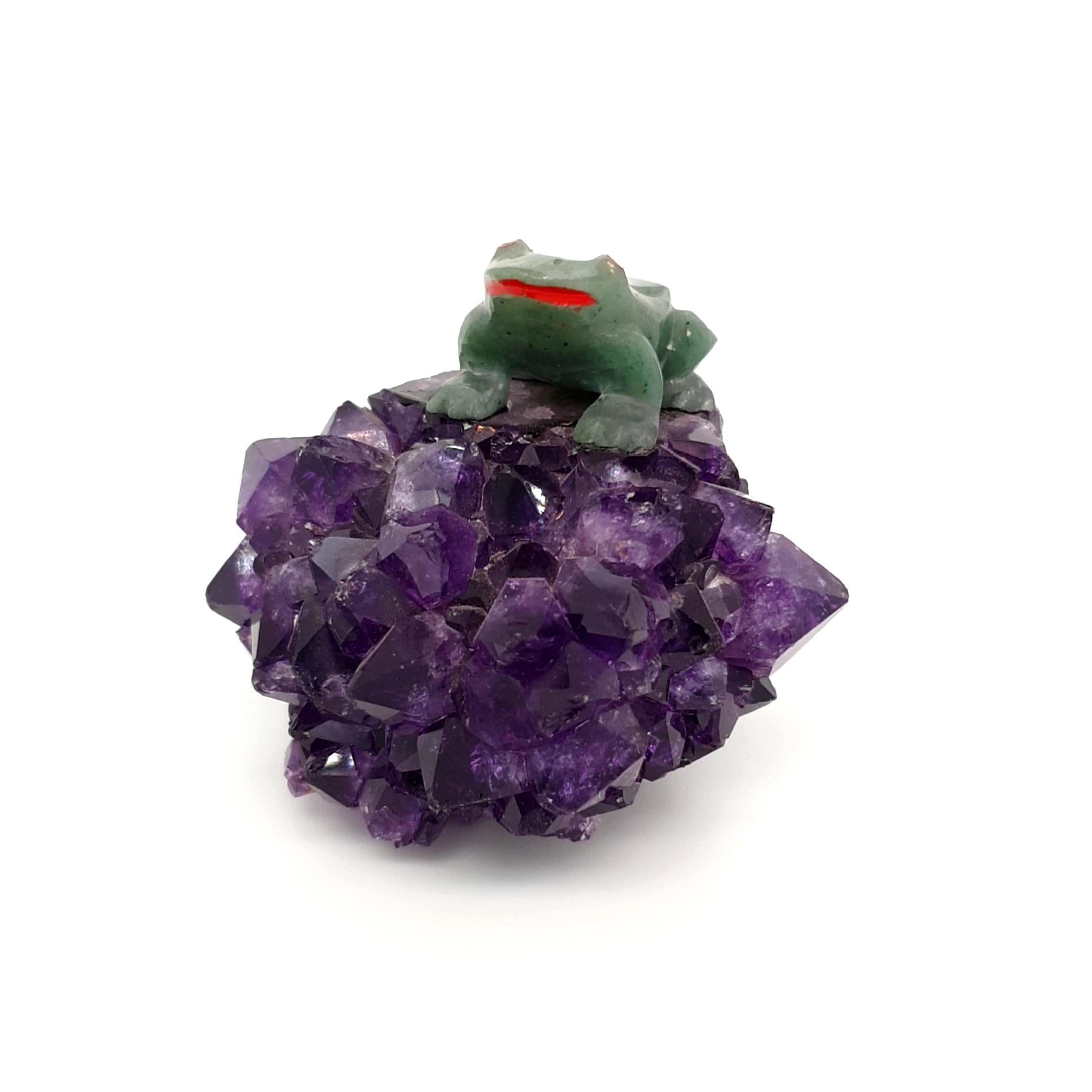 Dieser Amethyst Stalagtit hat rundherum kleine violette Kristalle. Obenauf ist ein Frosch aus Nephrit geschnitzt.

Maße: 47x56x48 mm
Gewicht: 11,9 gr.
