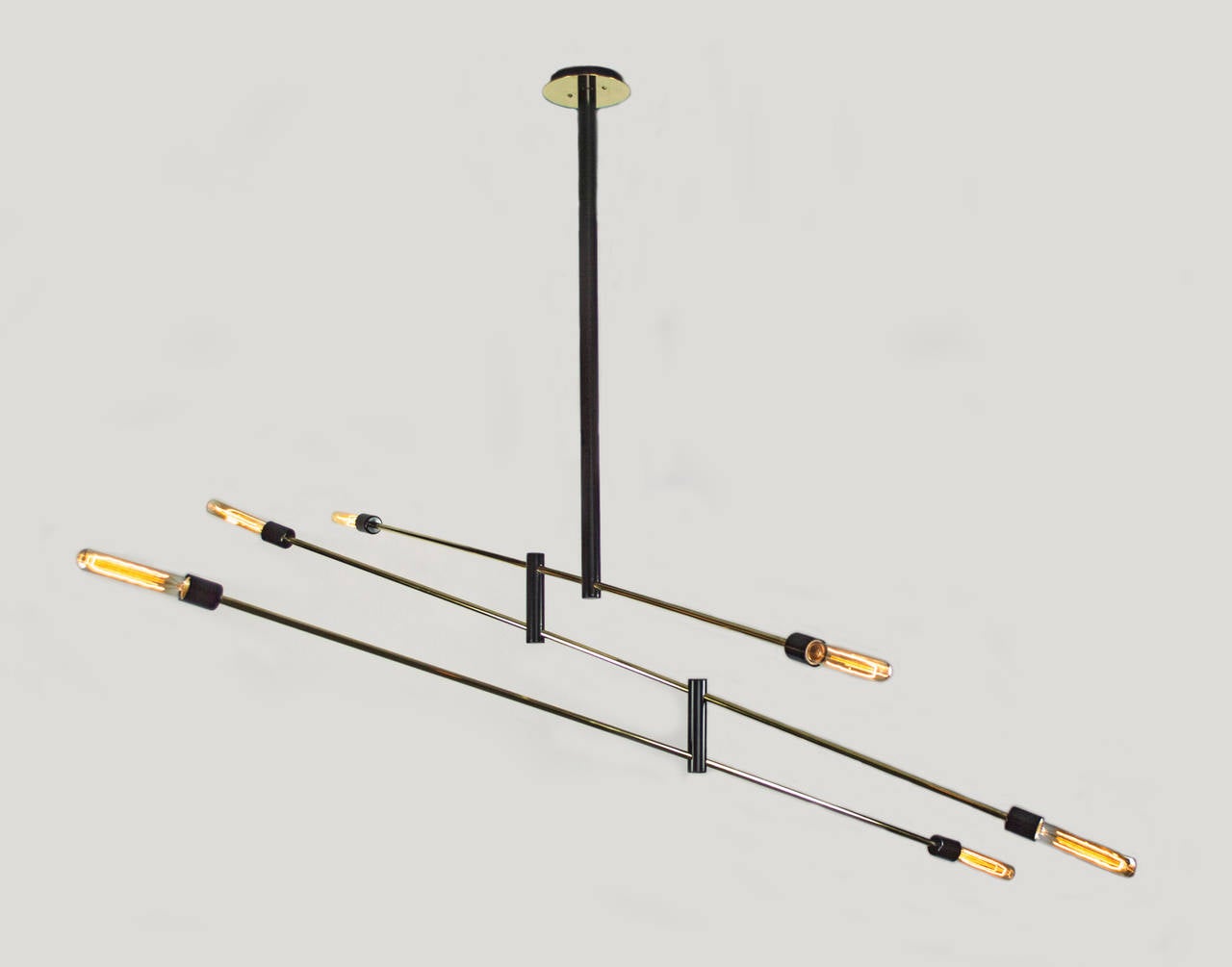 Simplicity at its finest. This distinctive chandelier is a dynamic presence in any room. The light is articulated which allows it to be moved like a mobile to create various Silhouettes. The black enameled frame with its brass tubing and canopy