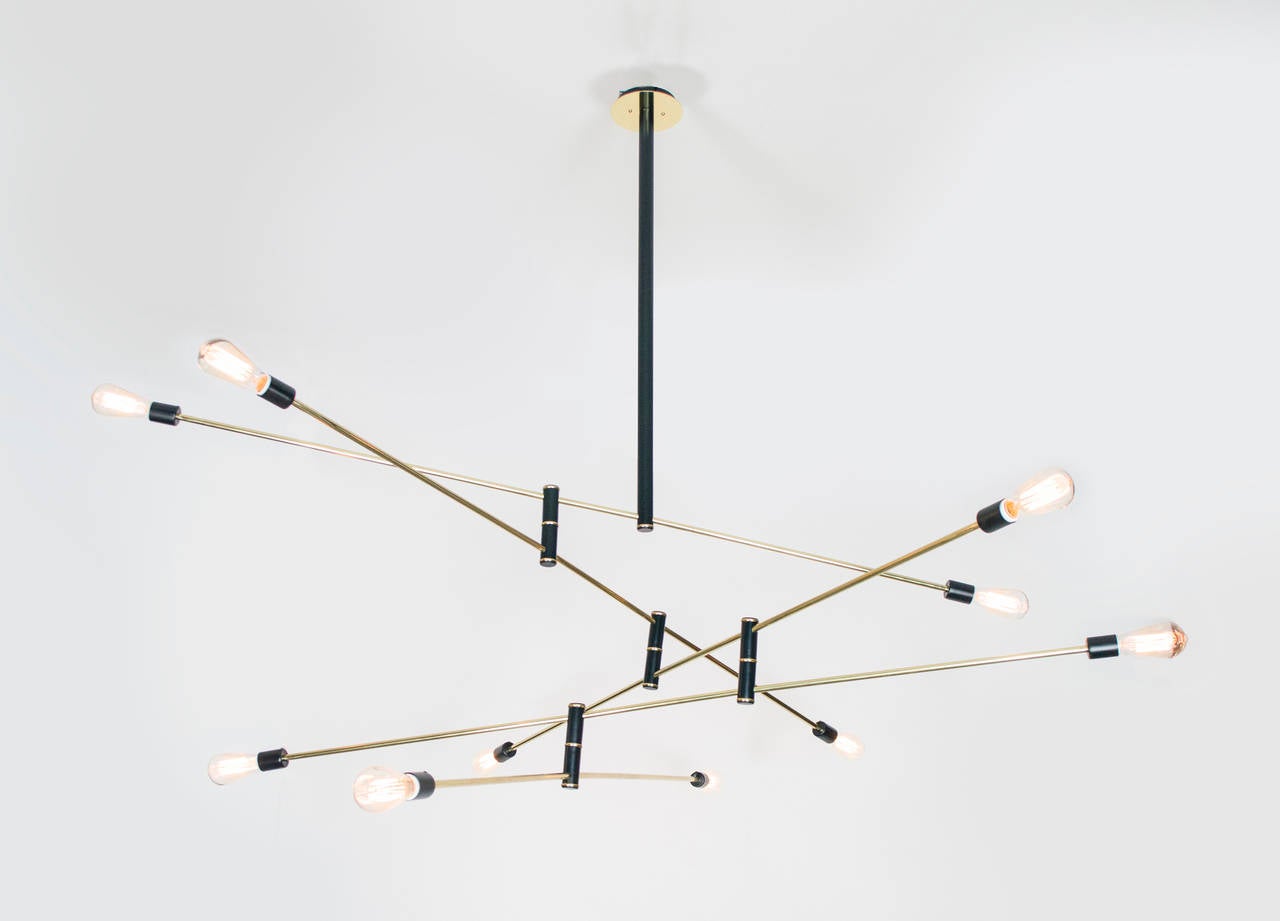 Simplicity at its finest. This distinctive chandelier is a dynamic presence in any room. The light is articulated which allows it to be moved like a mobile to create various silhouettes. The black enameled frame with its brass tubing and canopy