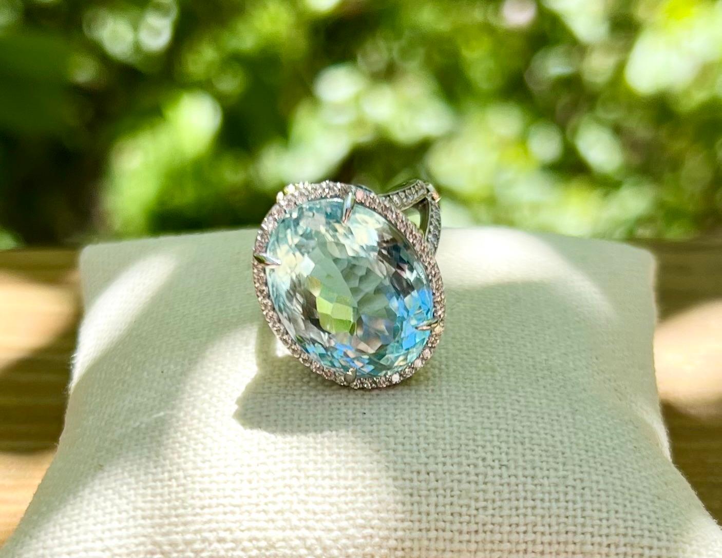 One 18 karat white gold (stamped 18K) ring by Stambolian, set with one 20. carat oval aquamarine measuring 21mm x 16mm, surrounded by a halo of one hundred fourteen round brilliant cut diamonds, approximately 1.33-carat total weight with matching