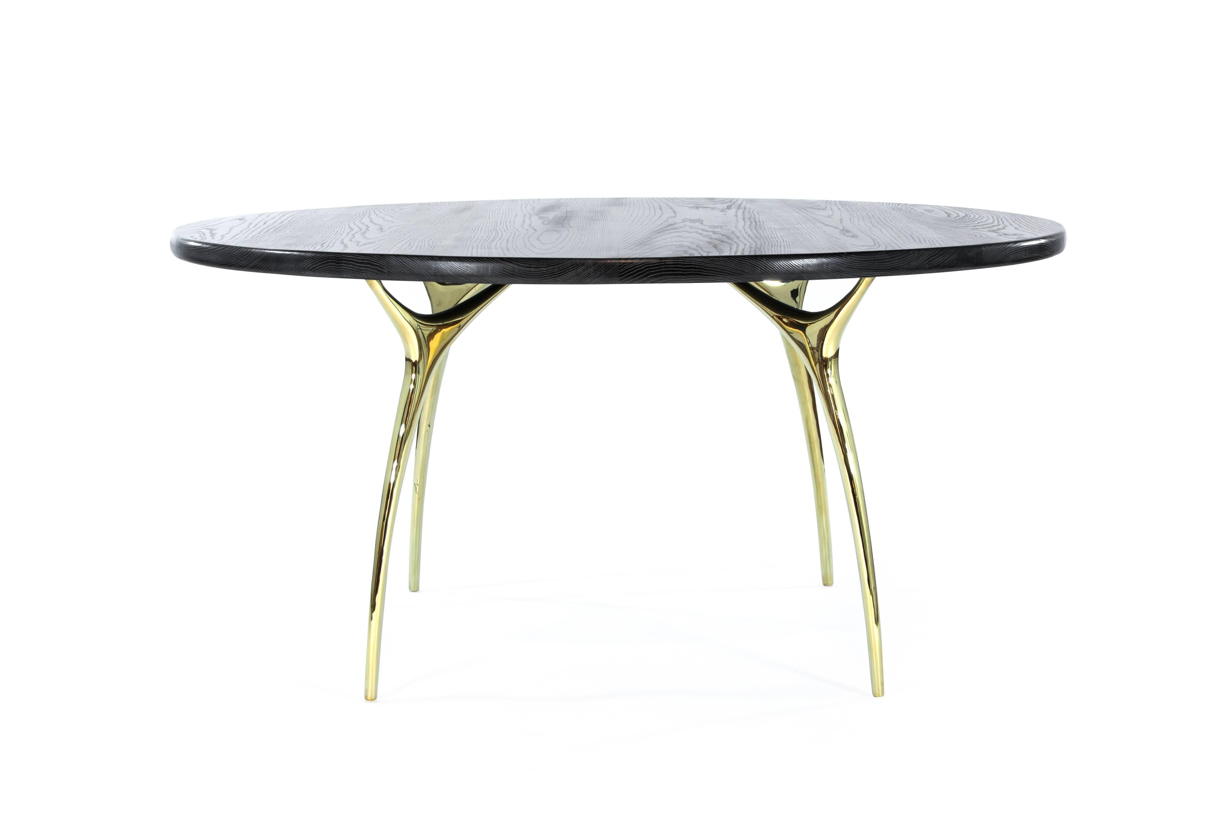 The Crescent Dining Table captures Gio Ponti’s Italian design aesthetic with gleaming metal and fluid curves. Four polished brass legs feel surprisingly organic, like delicate stalks that split and expand into slim branches. This delicate base is